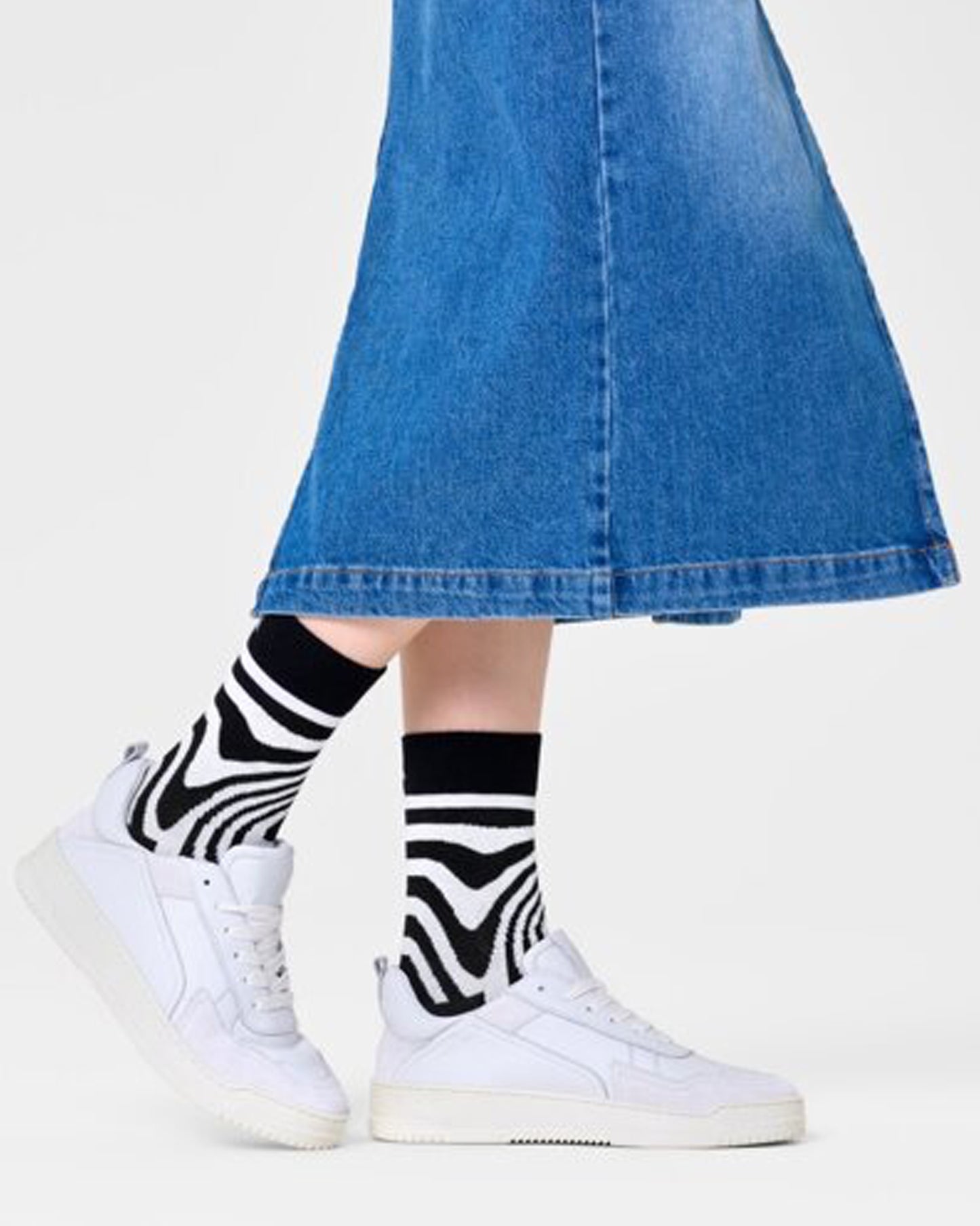 Happy Socks P000737 Dizzy Socks - Black cotton crew length ankle socks with a swirling psychedelic style linear pattern in white. Worn with denim skirt and white trainers.