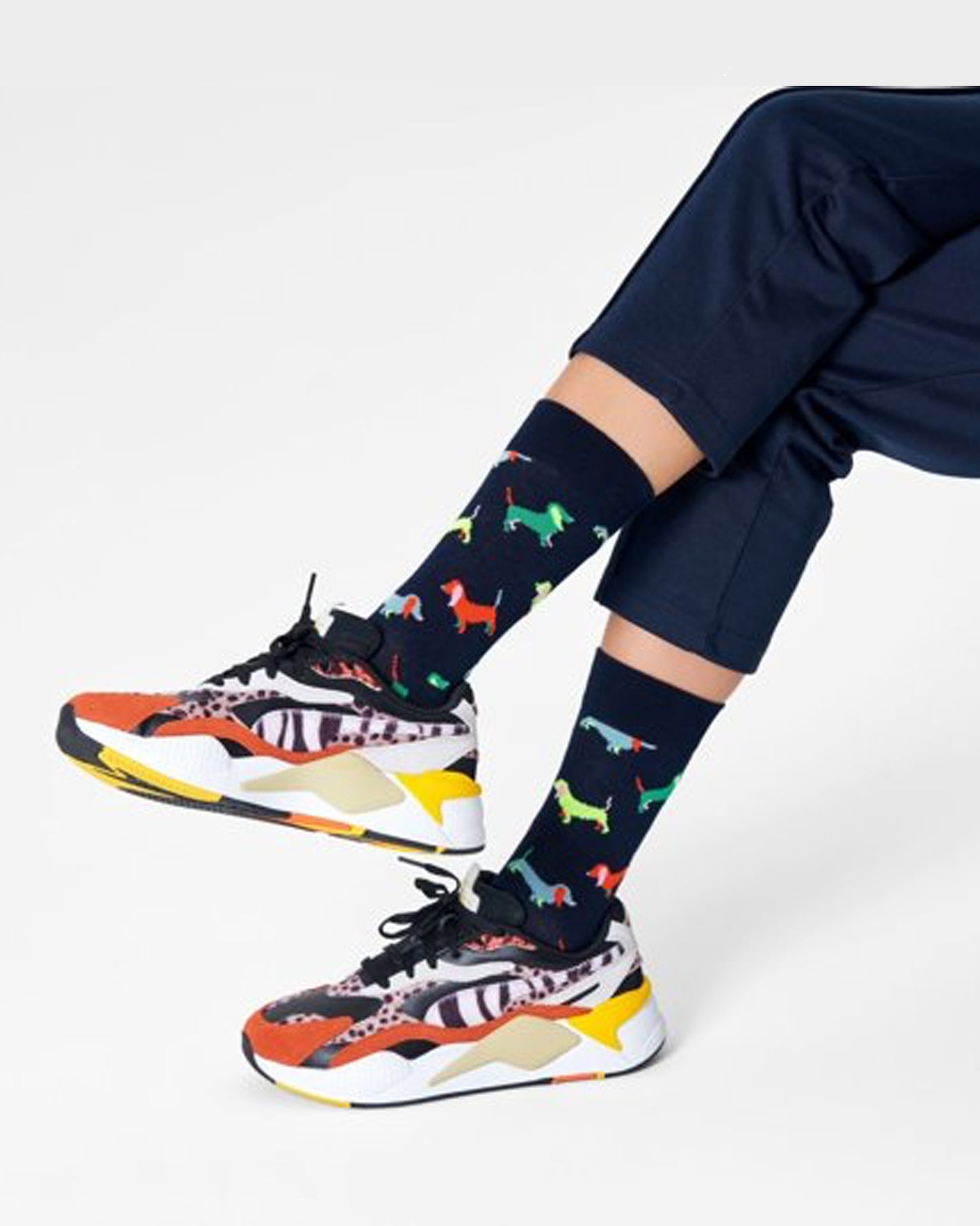 Happy Socks PUL01-6500 Puppy Love Sock - Dark navy cotton crew length ankle socks with a multicoloured dachshund type pattern. Worn with colourful chunky trainers and navy cropped pants.