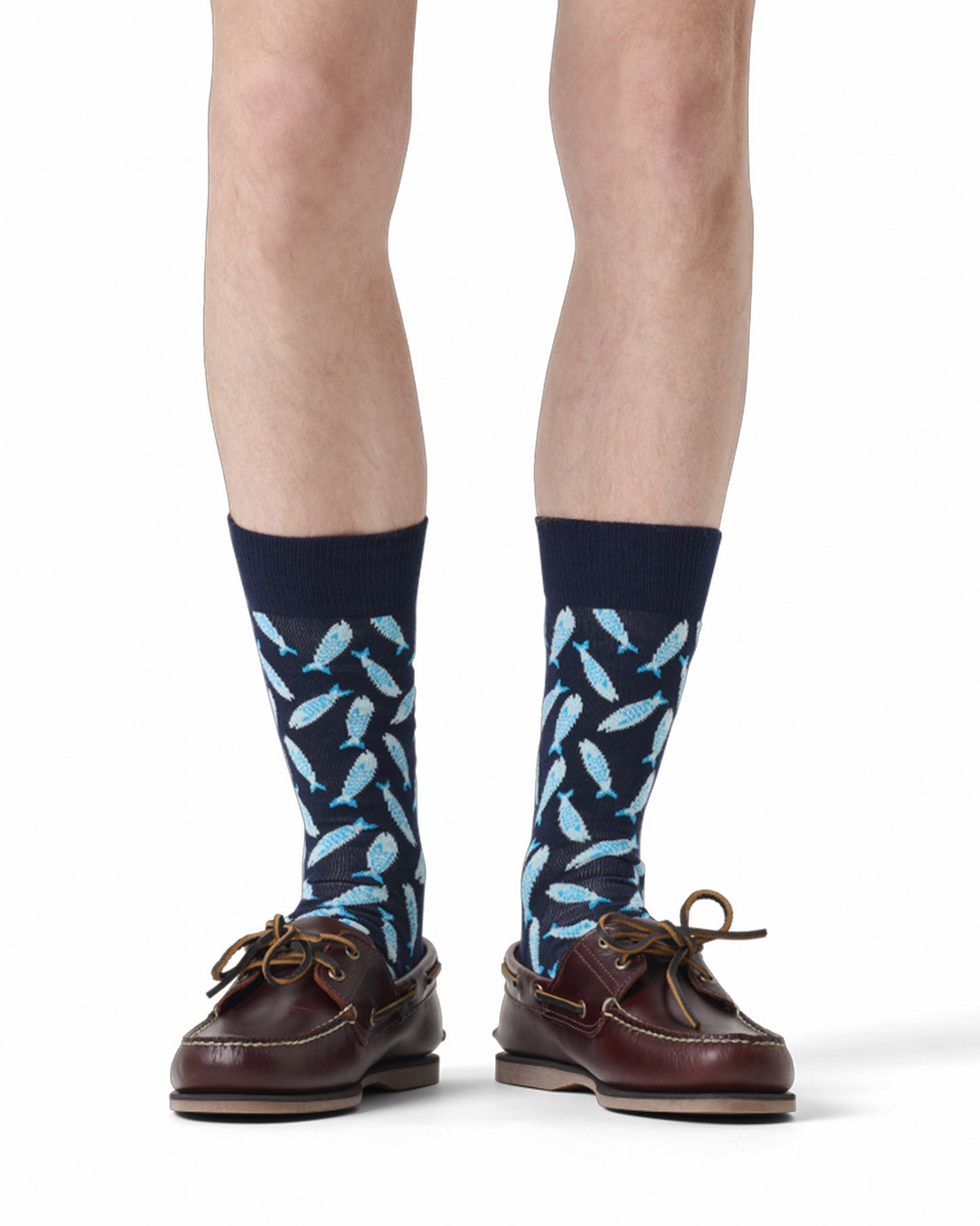 Navy socks with light blue fish pattern worn with brown shoes on a white background