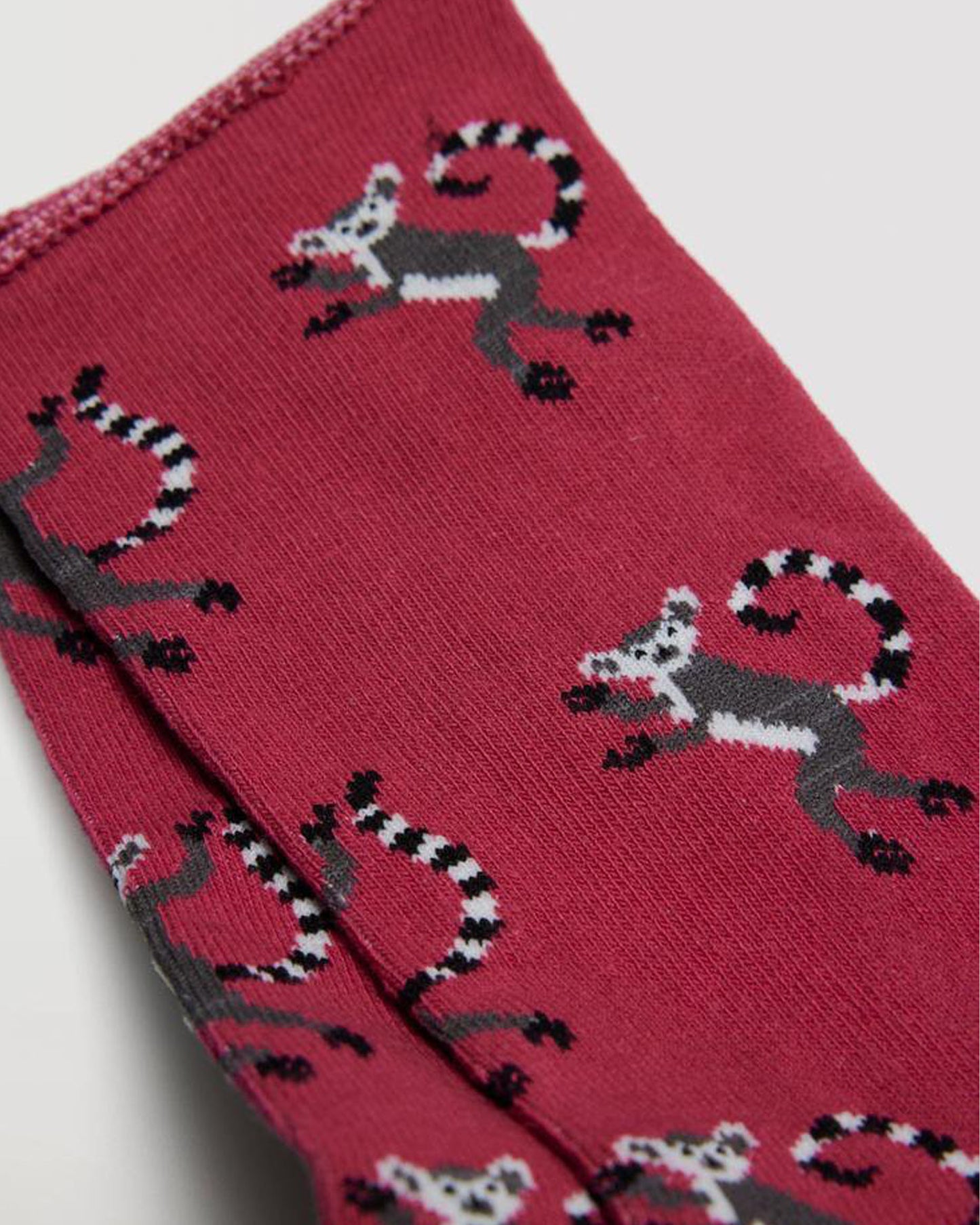 Ysabel Mora 12880 Lemur Sock - Dark red cotton socks with an all over lemur monkey pattern in grey, white and black, shaped heel, flat toe seam and no cuff edge roll. Close up detail.