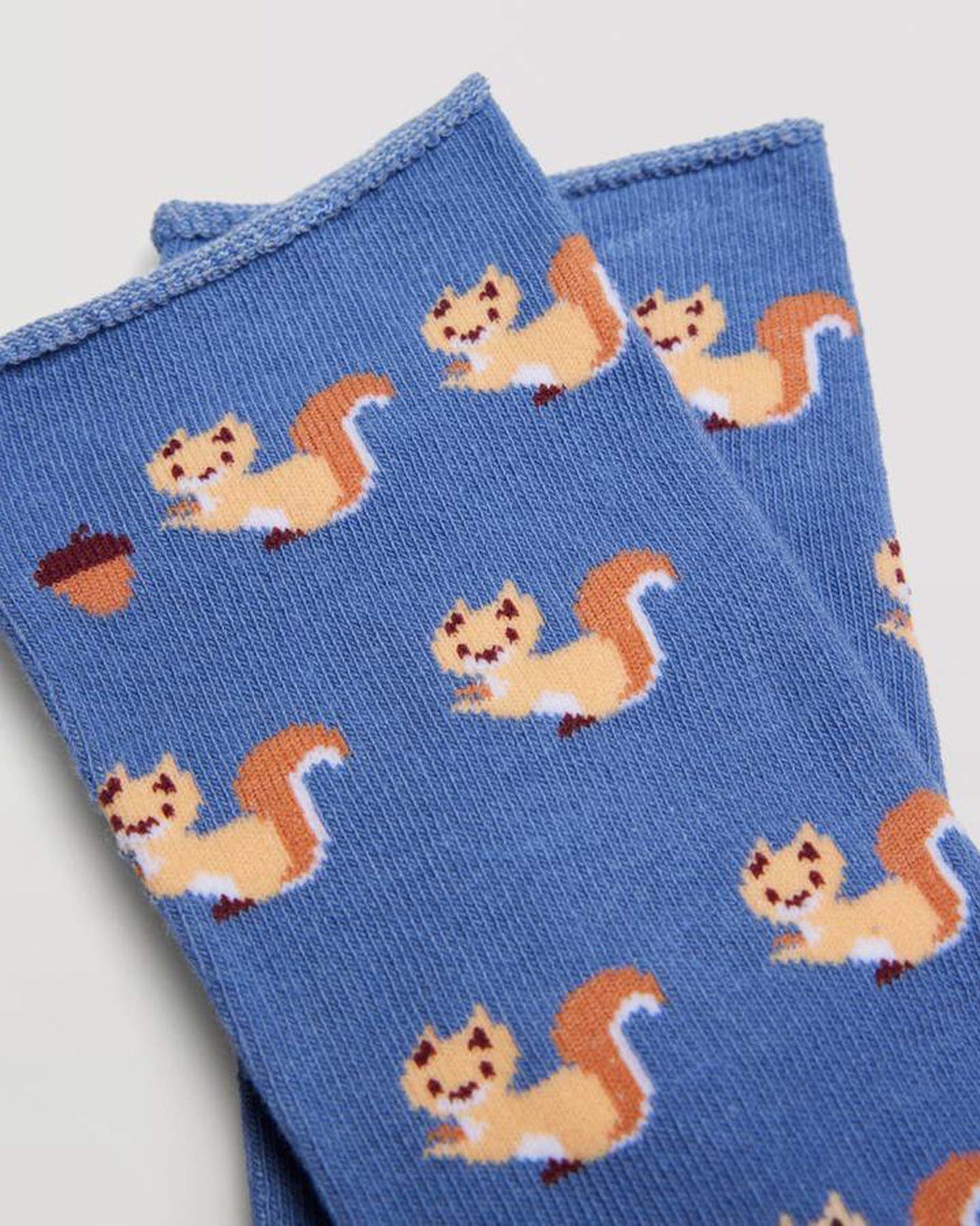 Ysabel Mora 12880 Squirrel Sock - Blue cotton socks with an all over squirrel and acorn pattern in peach and rust, shaped heel, flat toe seam and no cuff edge roll. Close up of soft roll top cuff.