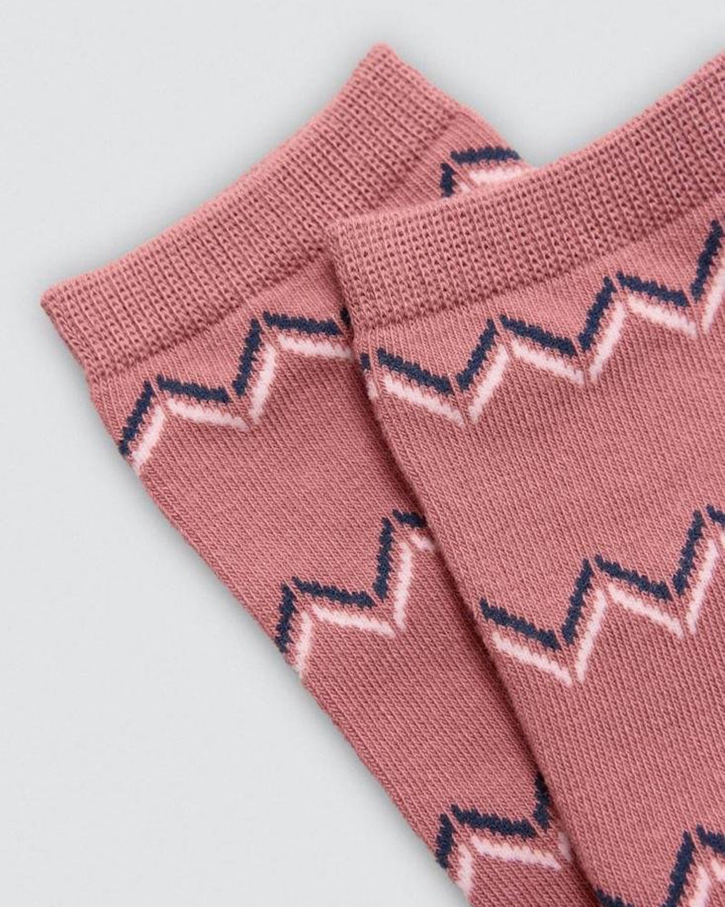 Pink socks with zigzag pattern on a light gray background
