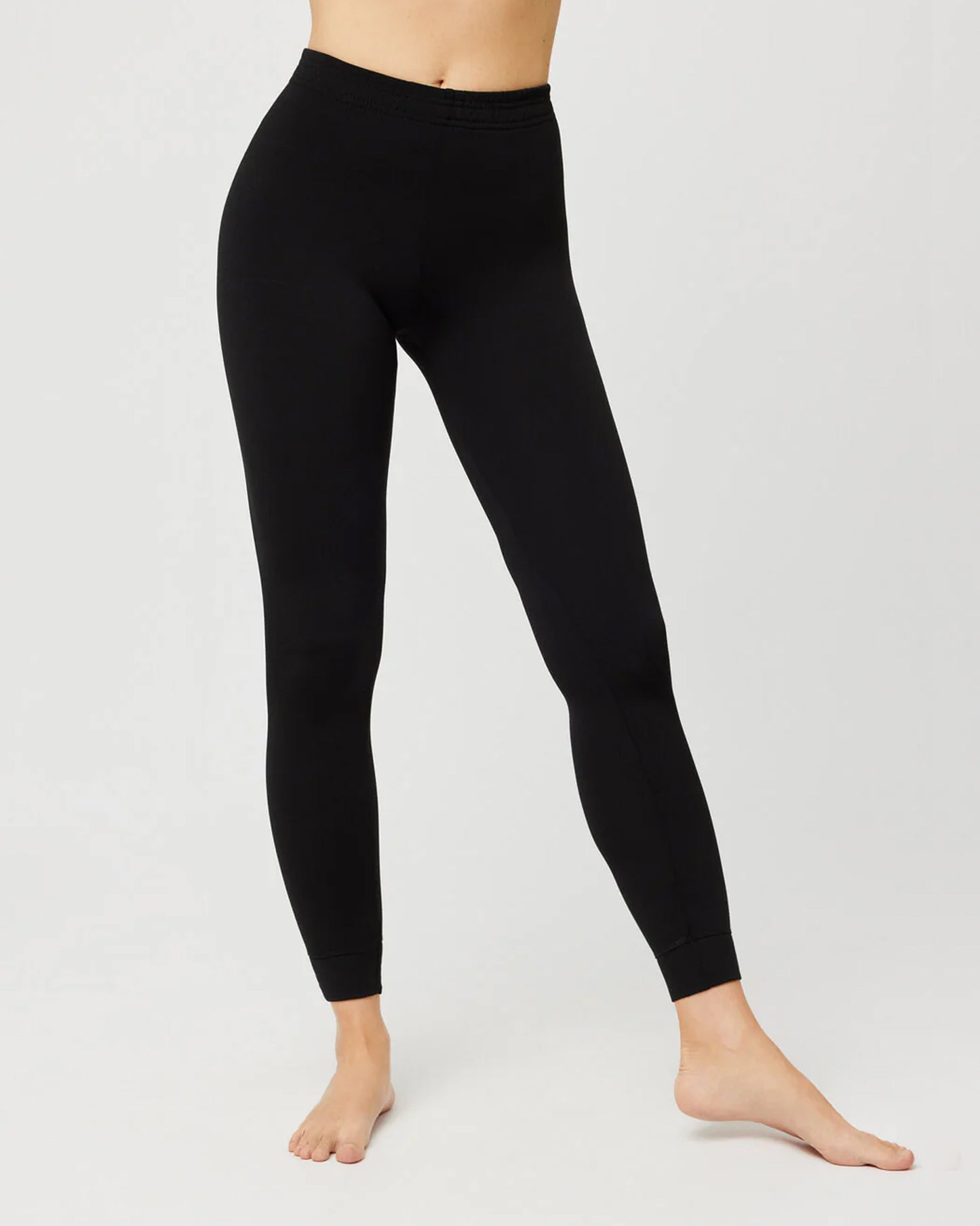 Black thermal fleece lined leggings worn by a person on a white background