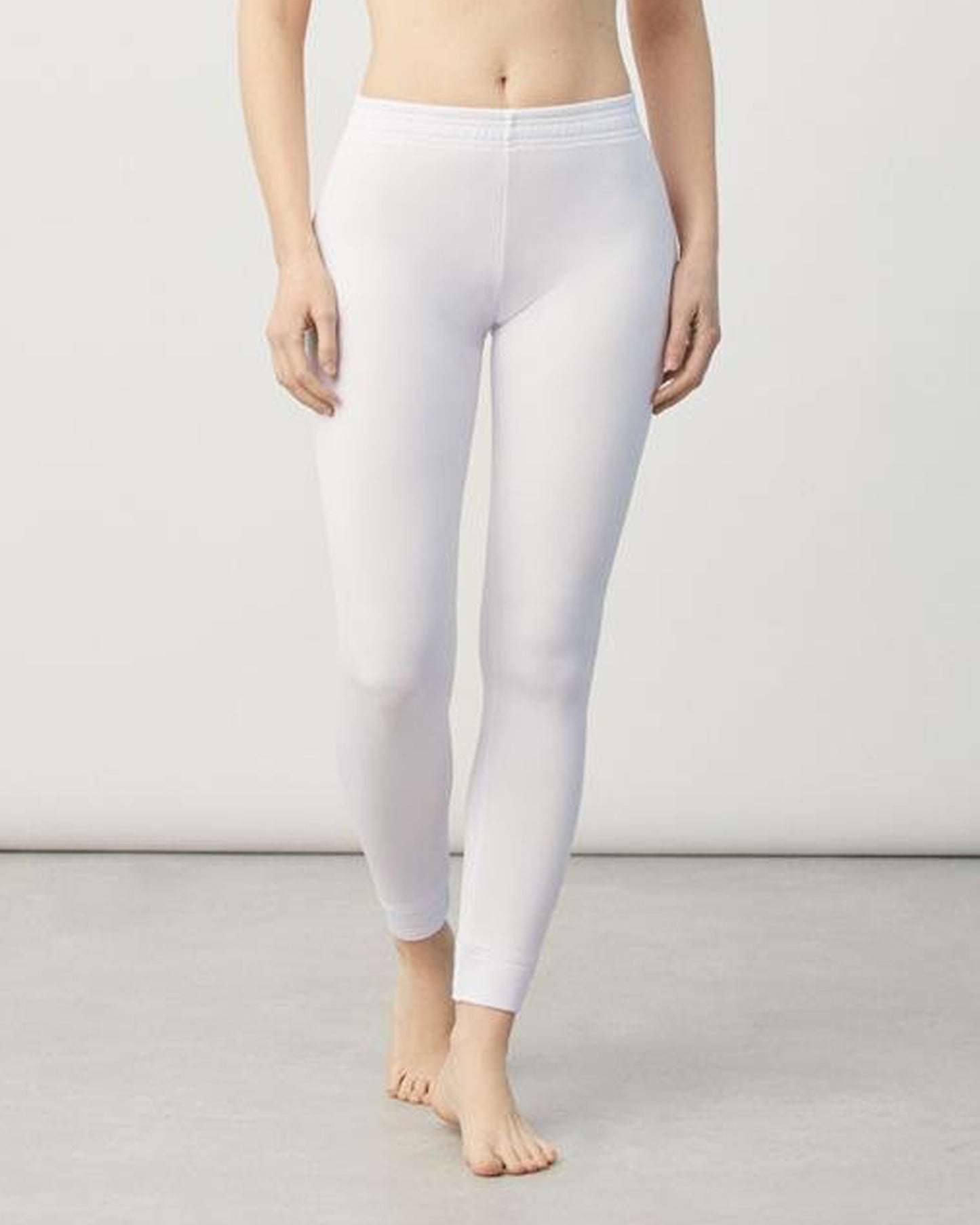 Person wearing white leggings on a plain background