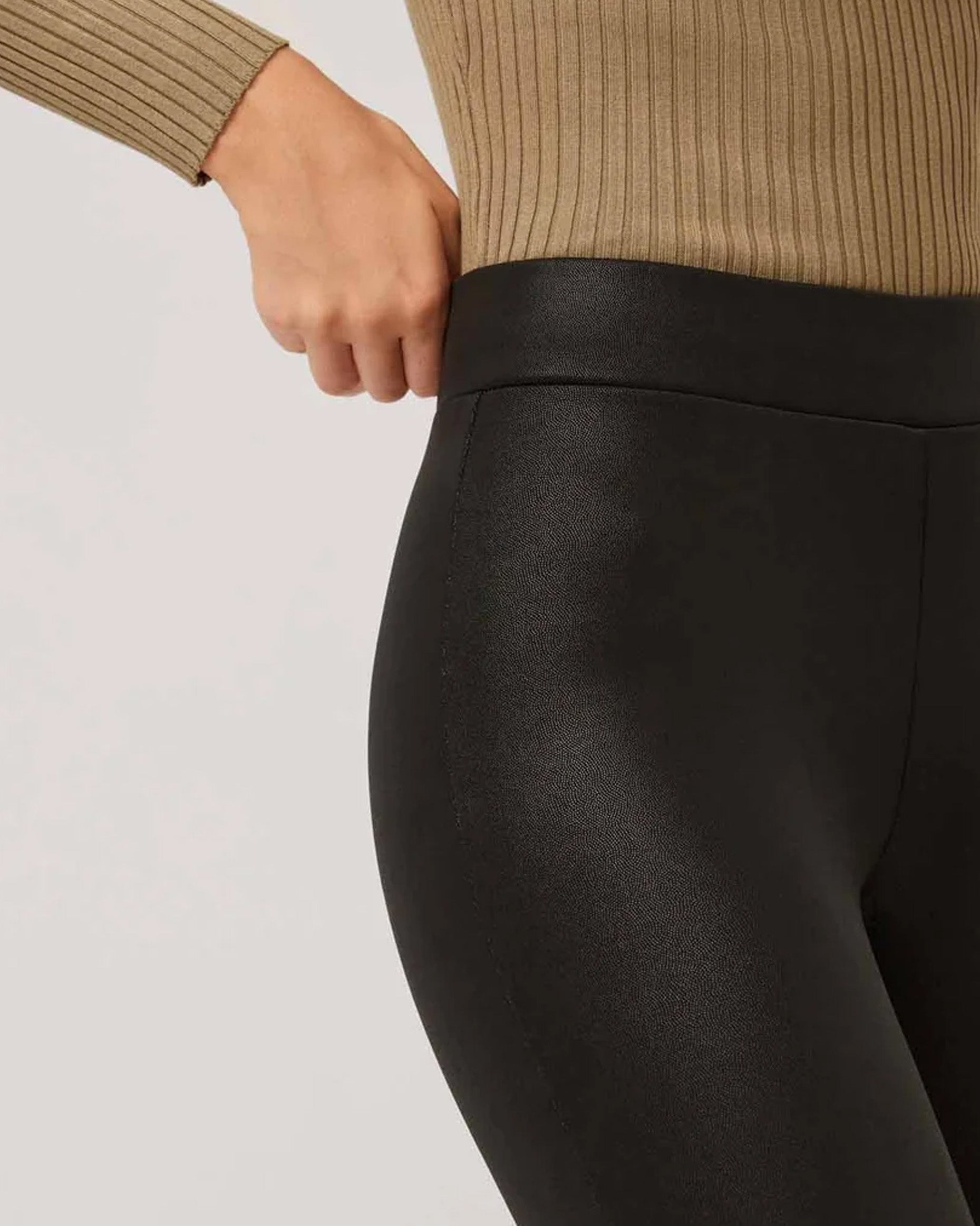Black high waisted trouser leggings with faux leather look, worn with beige rib top.