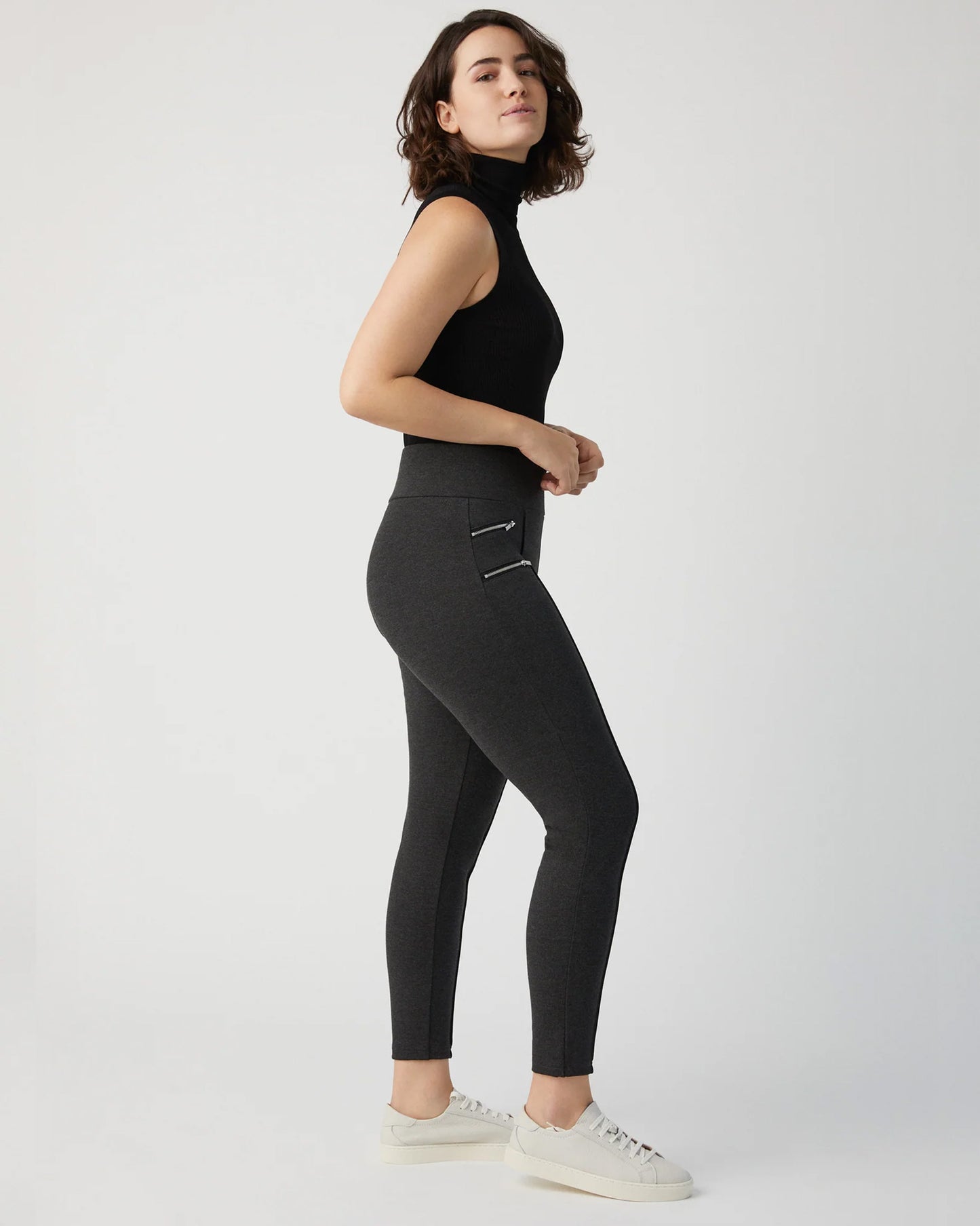 Ysabel Mora 70273 Leggings - Dark fleck grey jodhpur style high waisted leggings with silver side zips, raised centre seam down the leg and deep slimming waist band. Worn with black turtle neck top and white sneakers, side view.