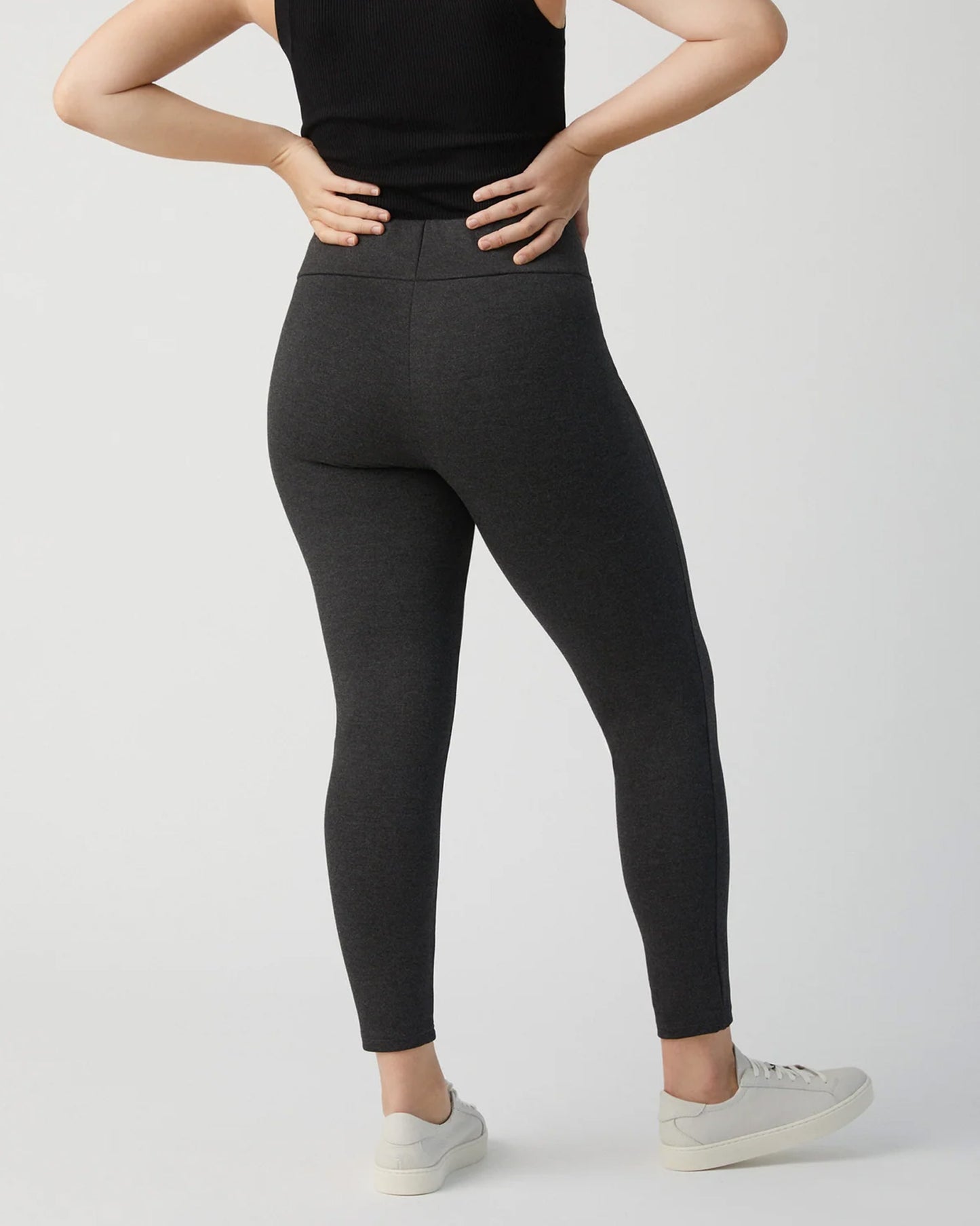 Ysabel Mora 70273 Leggings - Dark fleck grey jodhpur style high waisted leggings with silver side zips, raised centre seam down the leg and deep slimming waist band. Worn with black tank top and sneakers, back view.