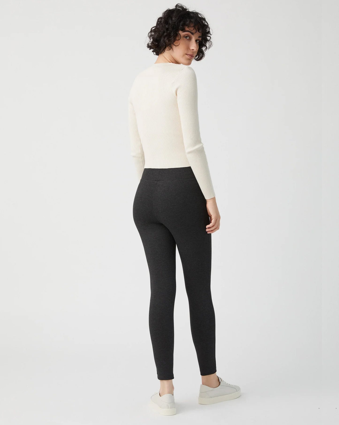 Ysabel Mora 70273 Leggings - Dark fleck grey jodhpur style high waisted leggings with silver side zips, raised centre seam down the leg and deep slimming waist band. Worn with cream ribbed sweater and sneakers. Back view.