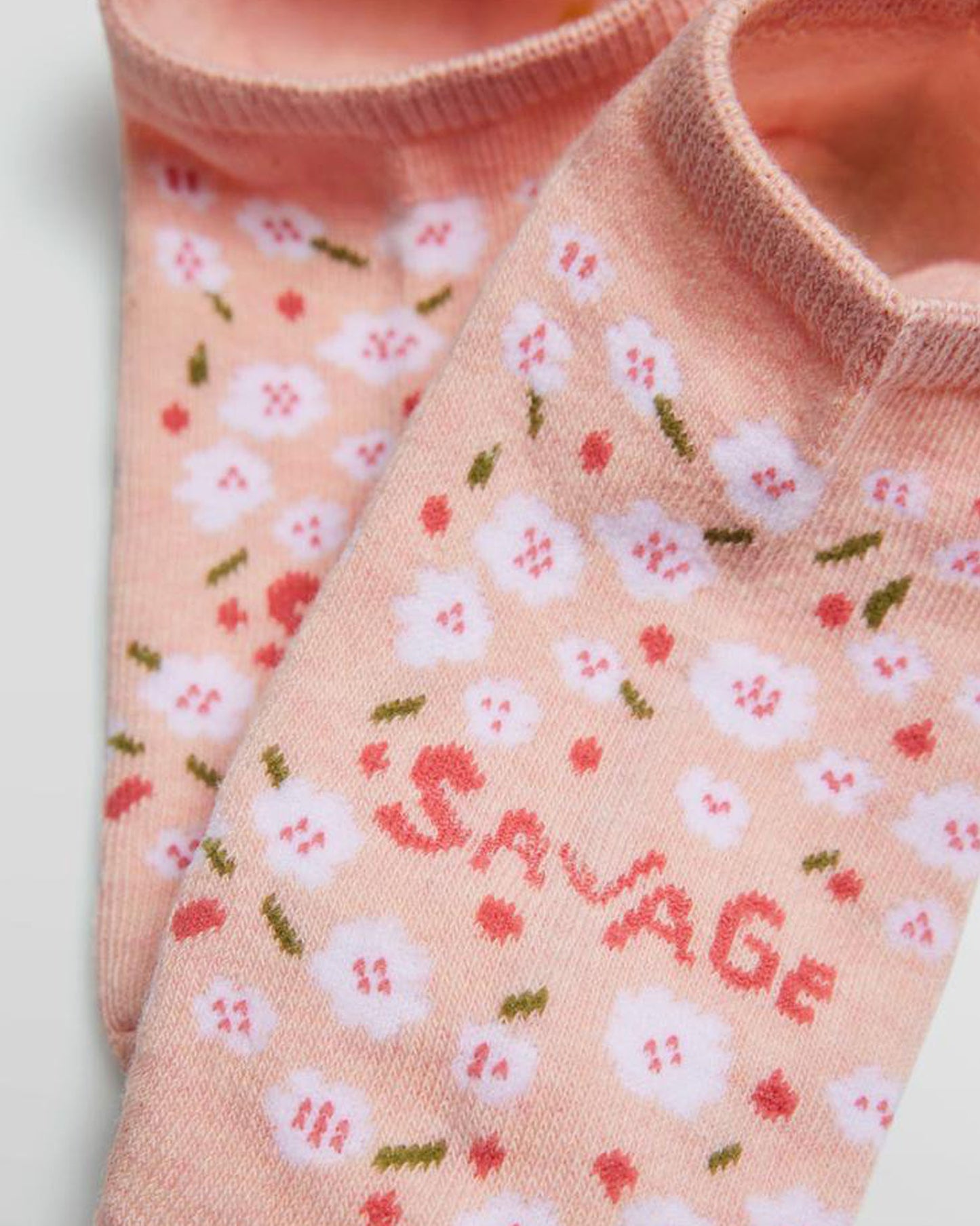 Floral-patterned socks with 'Savage' text on a light pink background with floral pattern.