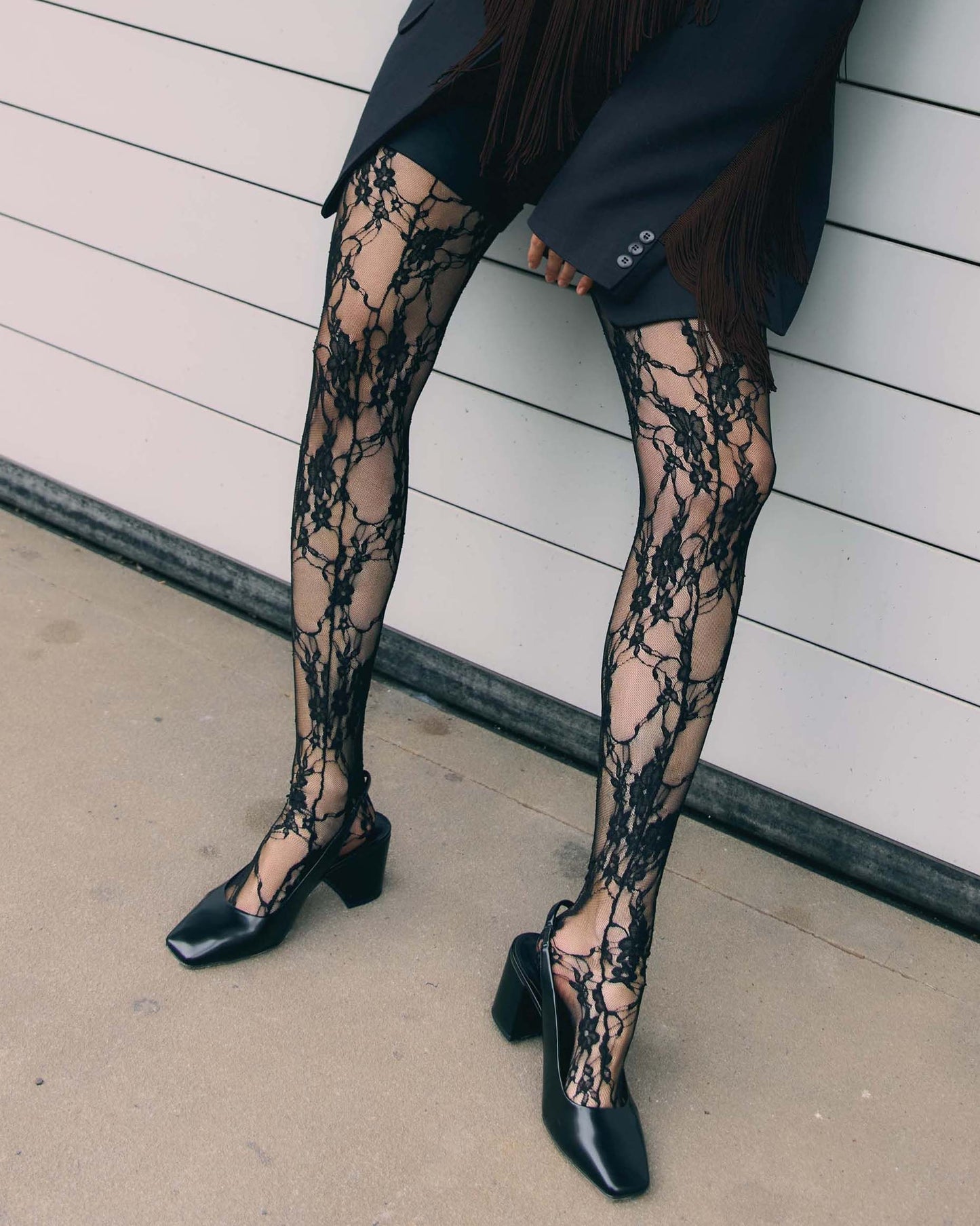 Fiore Donatella Tights - Black floral lace tights on a micro mesh/tulle background with a back seam. Worn with black square to block heel sling back shoes & black blazer and shorts.
