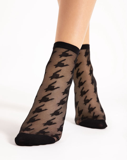 Sheer black houndstooth patterned socks with black cuffs and toes on a white background