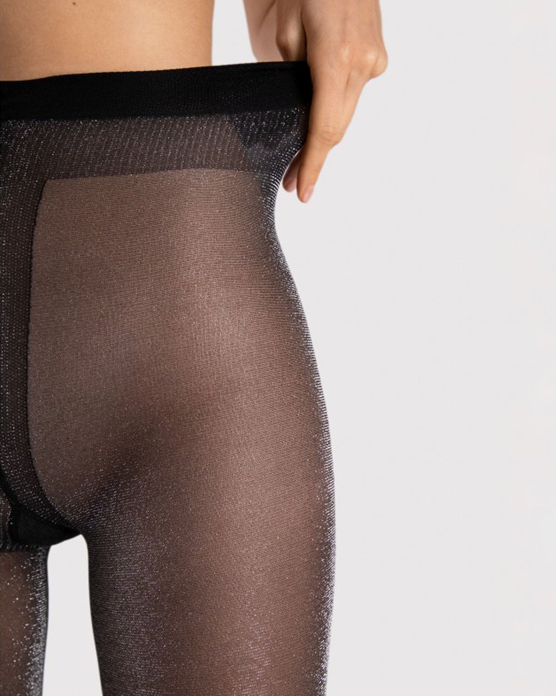 Sheer black tights with silver shimmer worn by a person on a light grey background