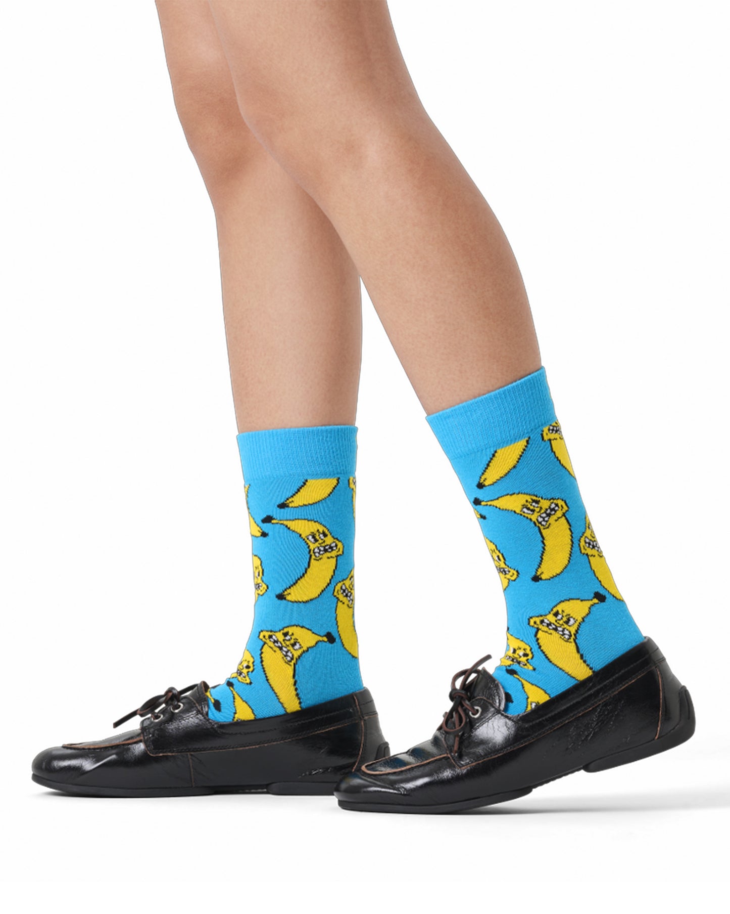 Blue socks with banana pattern worn by a person on a white background