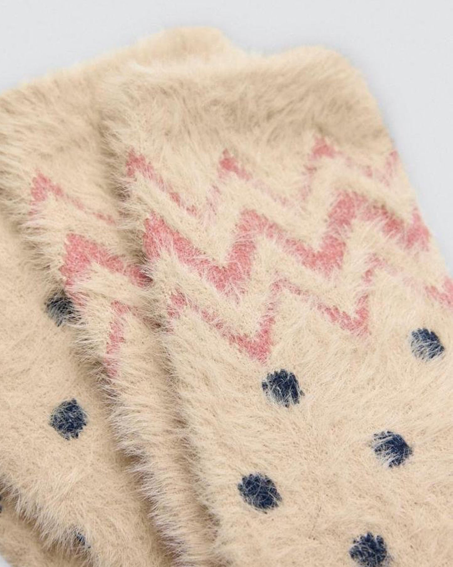 Close-up of a textured fluffy socks with pink zigzag pattern and navy dots on a light background