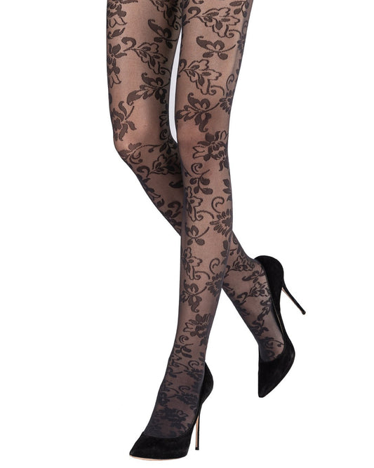 Sheer black floral patterned tights worn with black high heels on a white background