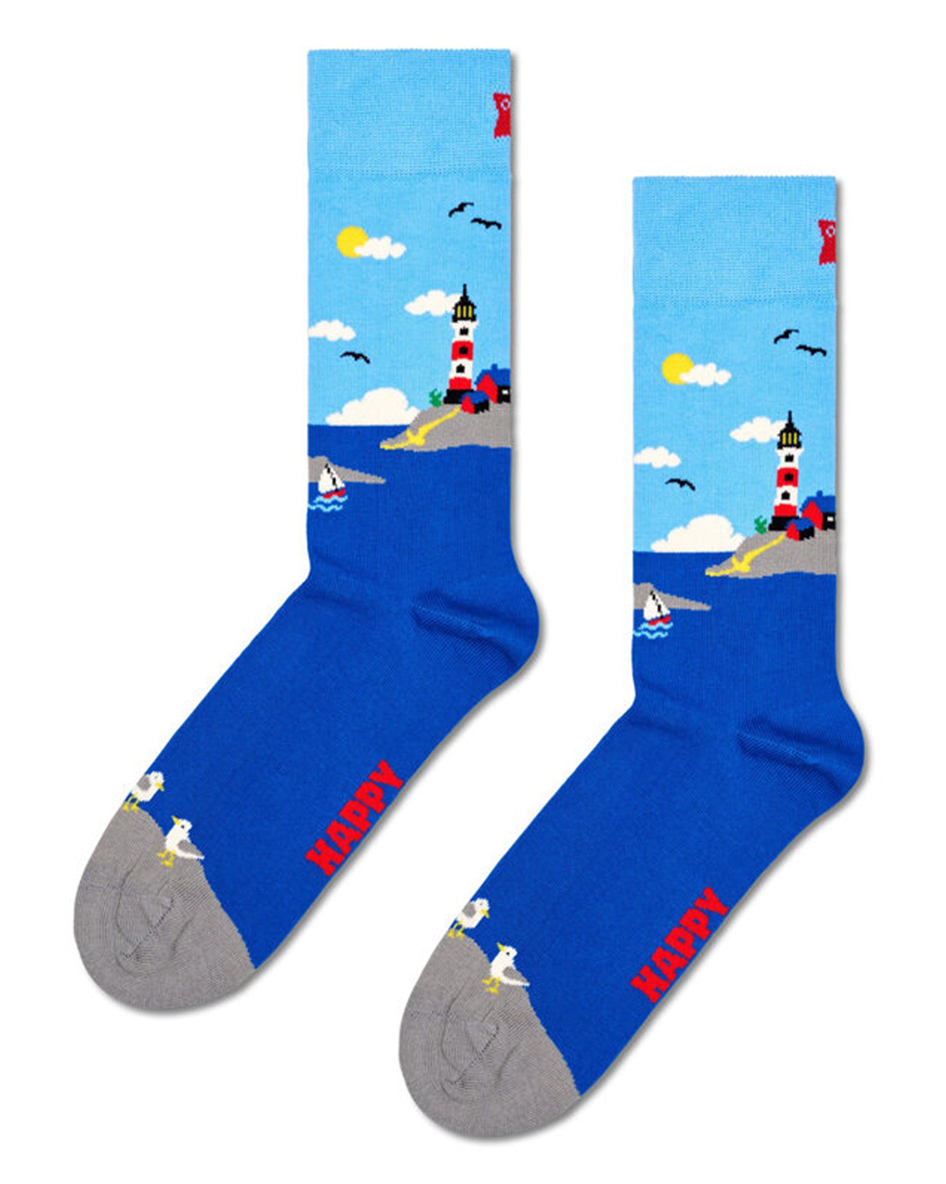 Happy Socks P001159 Light House Sock - Light sky blue cotton crew length ankle socks with a rugid rocky coastal scene design featuring a lighthouse, sail boat, clouds, sun and birds.