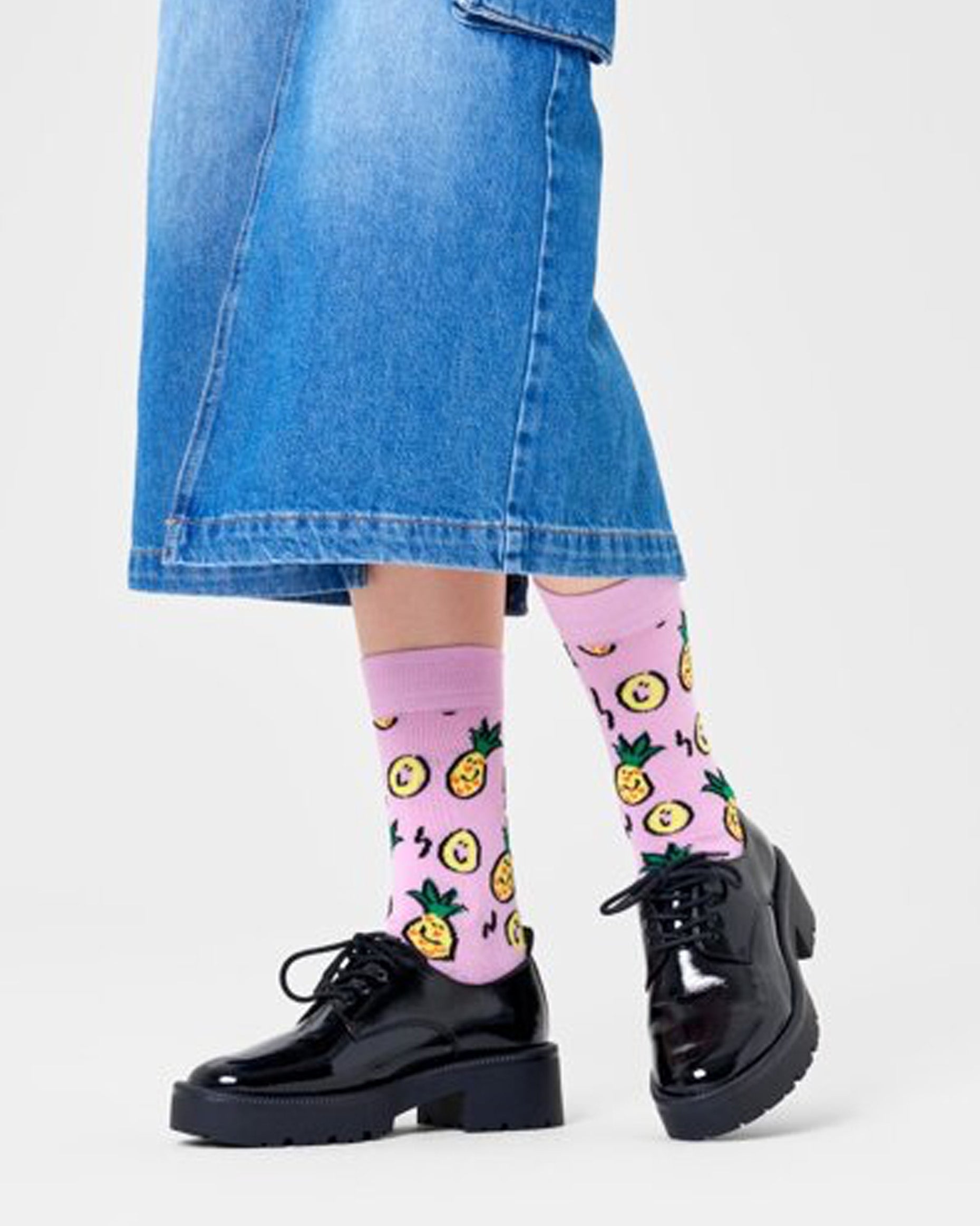 Happy Socks P000718 Pineapple Sock - Light lilac cotton crew length ankle socks with an all over pattern of smiling cartoon pineapples in shades of yellow, green and black. Worn with denim skirt and black chunky loafers.