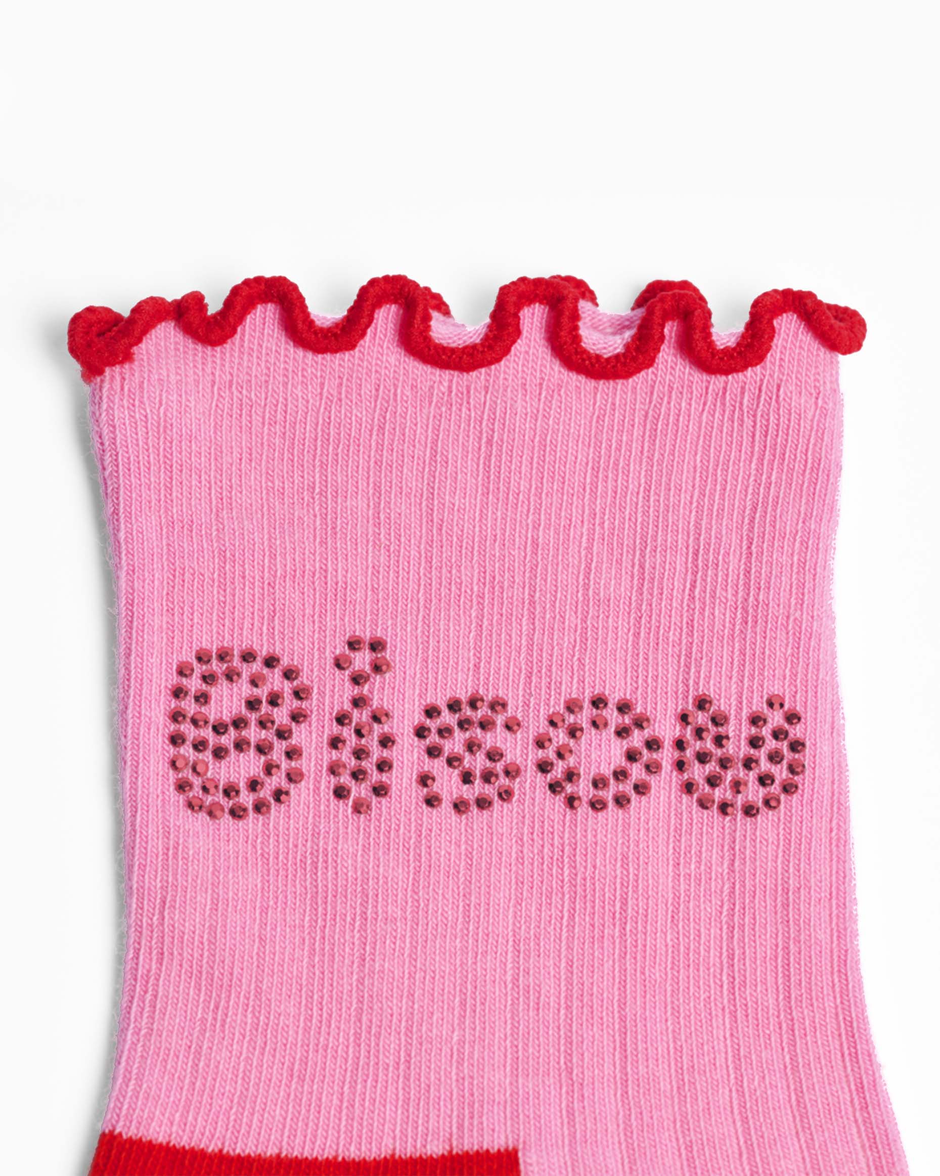 Pink ribbed sock with red frill trim and 'bisou' text on a white background