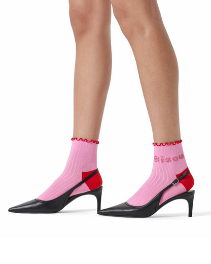 Pink socks with red trim worn with black high heels on a white background