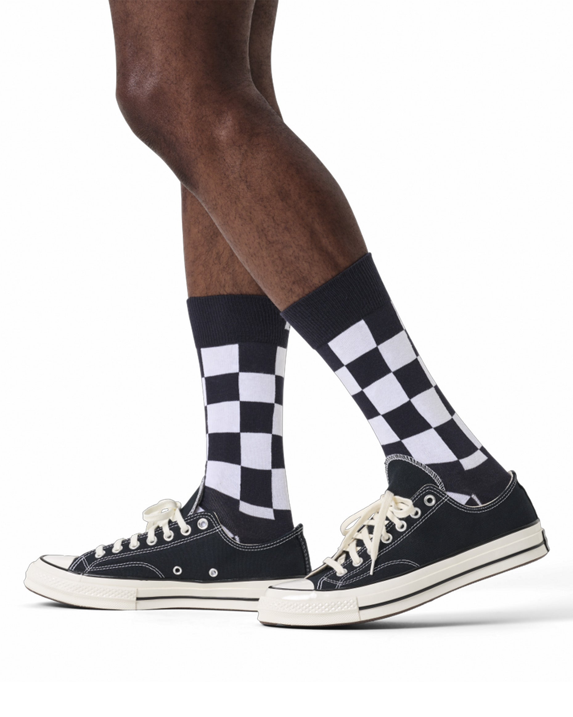 Checkered socks worn with black sneakers on a white background