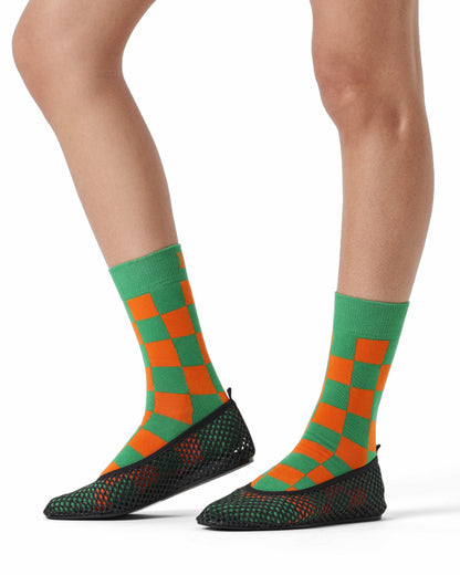 Green and orange checkered socks with black soles on a white background