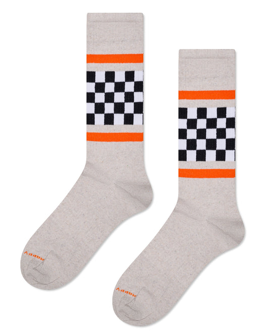 Oat coloured cotton crew length ankle socks with a ribbed texture, black and white checkered panel around the ankle with an orange stripe above and below it.