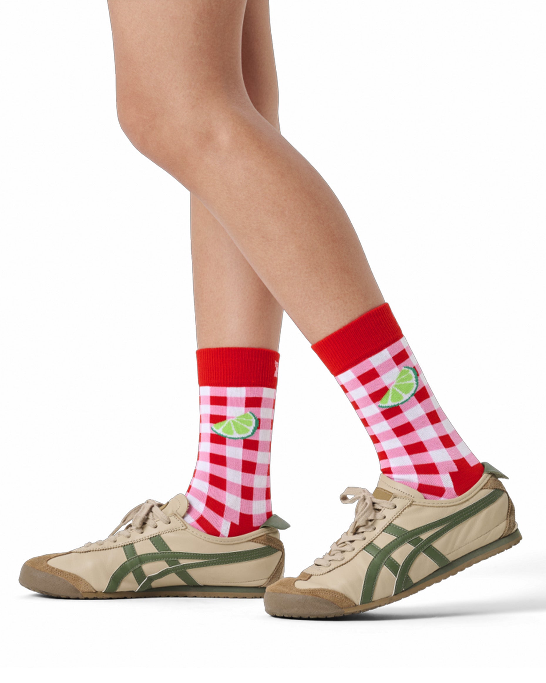 Red and white checkered socks with green accents worn with beige sneakers on a white background