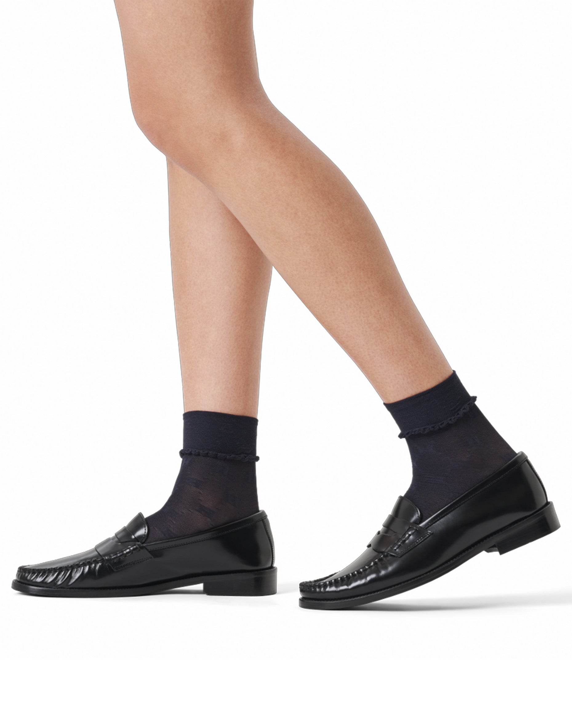 Black loafers worn with black socks on a white background