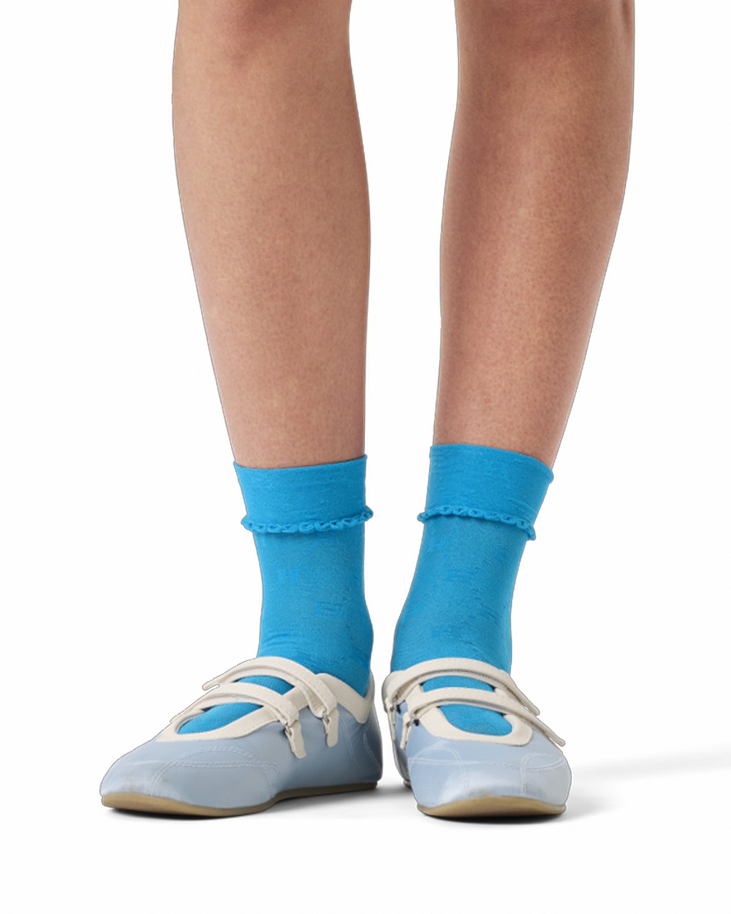 Blue socks worn with light blue shoes on a white background