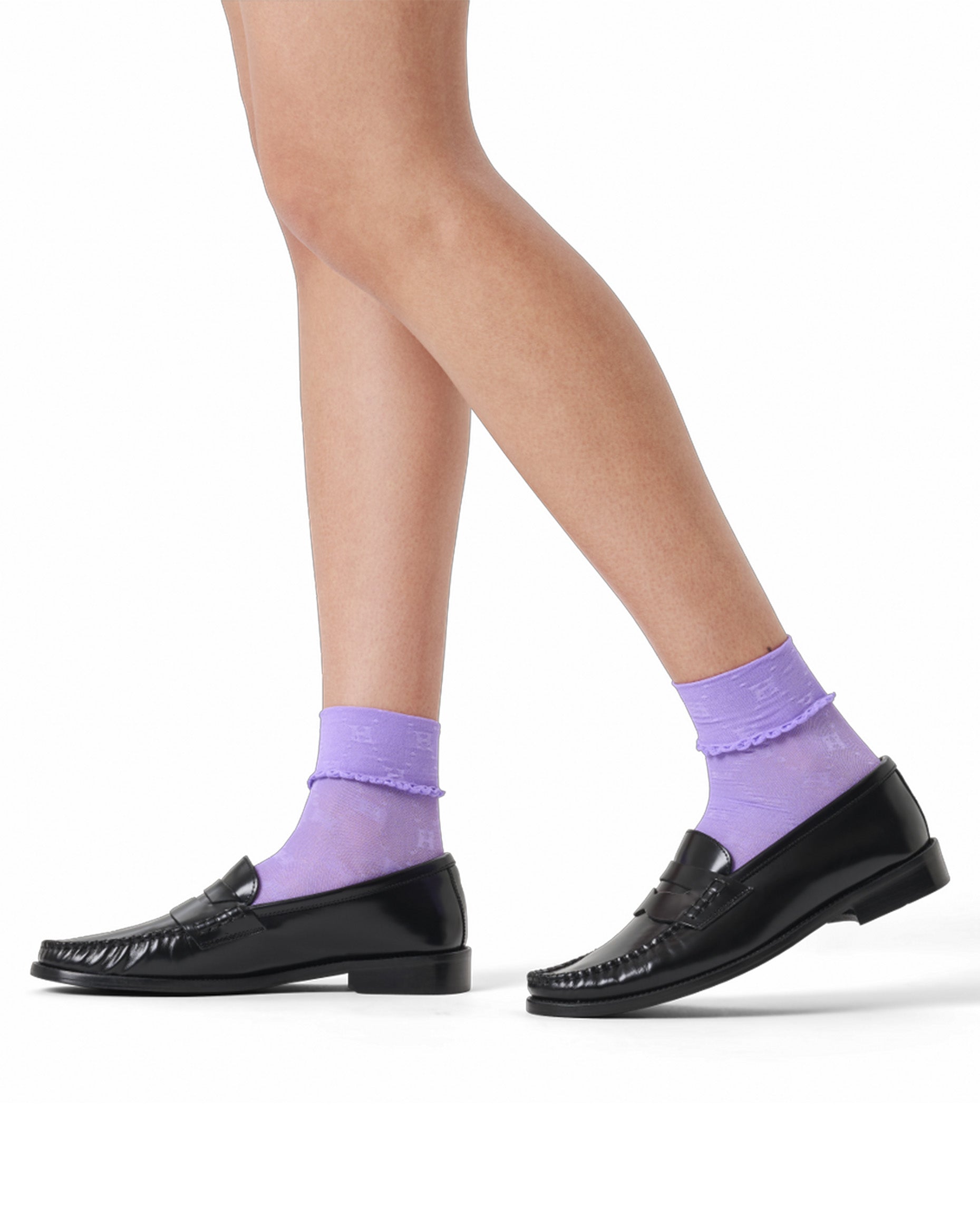 Person wearing black loafers and purple socks on a white background