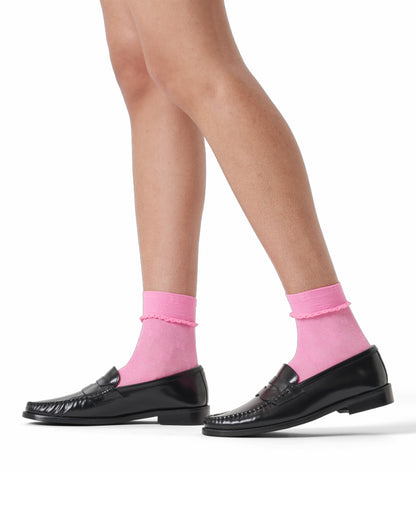 Black loafers with pink socks on a white background
