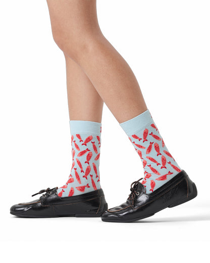 Person wearing light blue socks with red fish pattern and black shoes on a white background