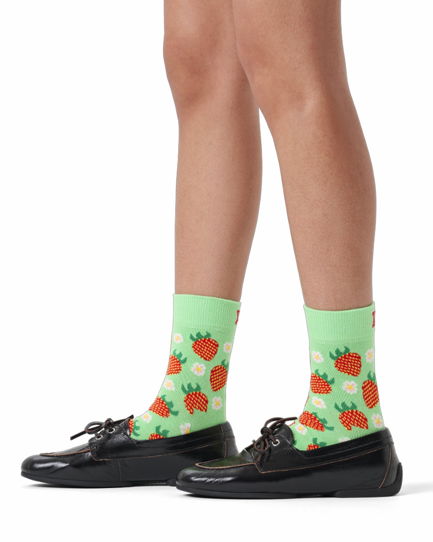 Green socks with strawberry pattern worn by a person on a white background