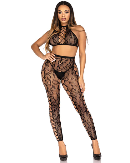 A woman modeling a two-piece black leopard print fishnet lingerie set consisting of a halter crop top and matching high-waisted footless tights 