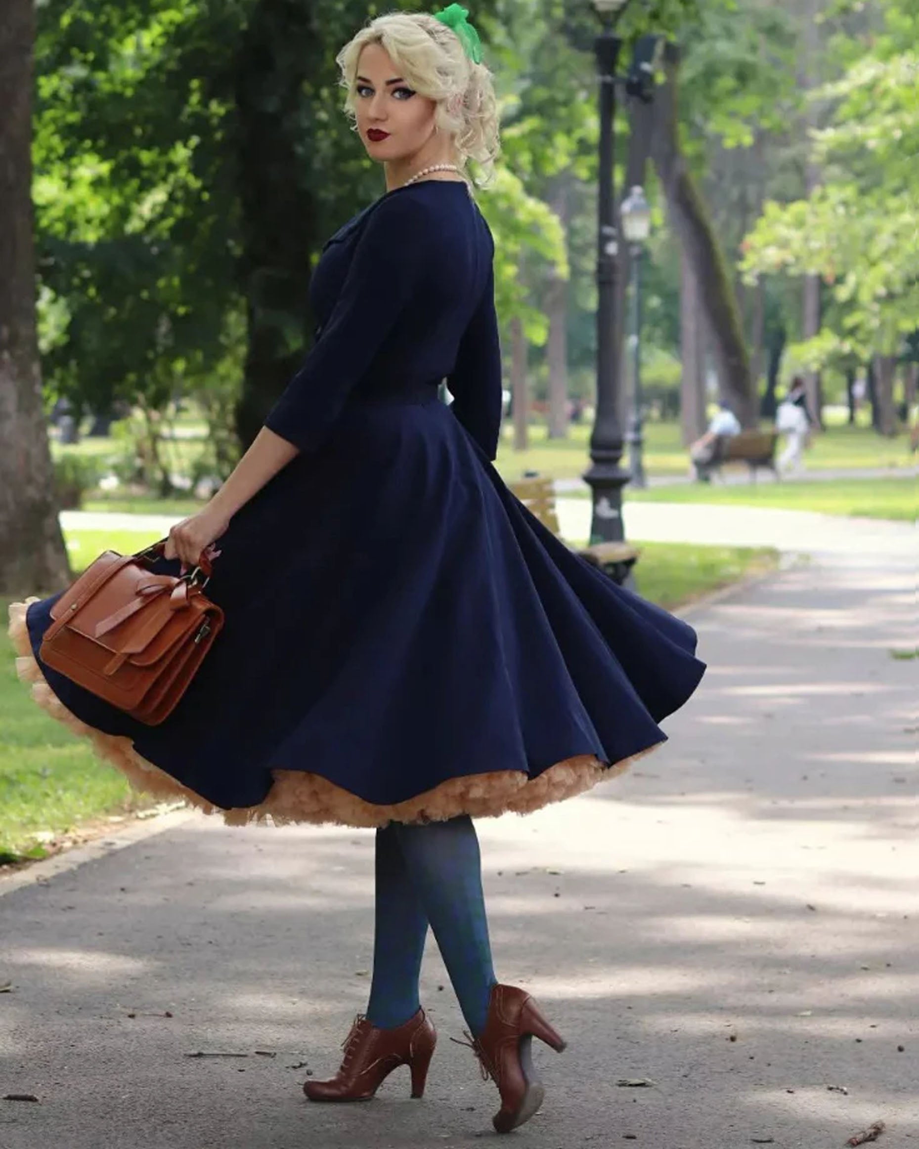 White opaque fashion tights with a green and navy tartan printed pattern. Worn with a navy a line dress with full rouched skirt, brown laced high heel shoes.