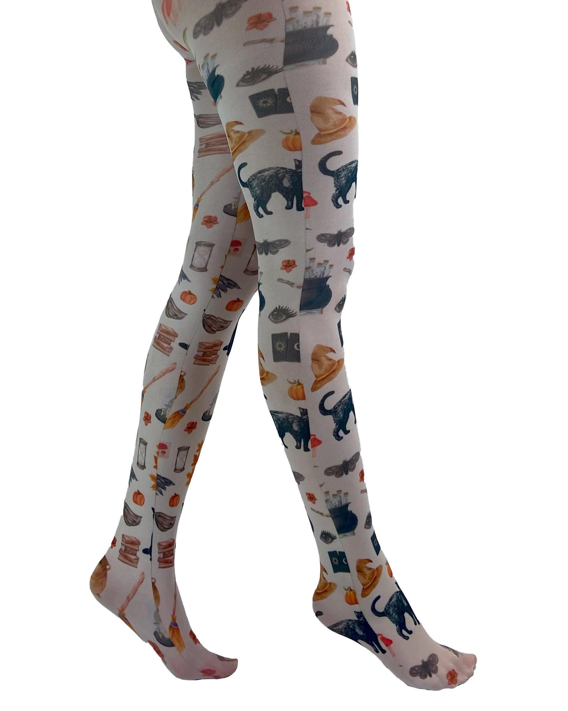 Pamela Mann Spells & Potion Tights - White opaque tights with an all over print of Victorian style Halloween themed illustrations, including pumpkins, cats, witches hats, broom sticks, cauldrons etc. Side view.