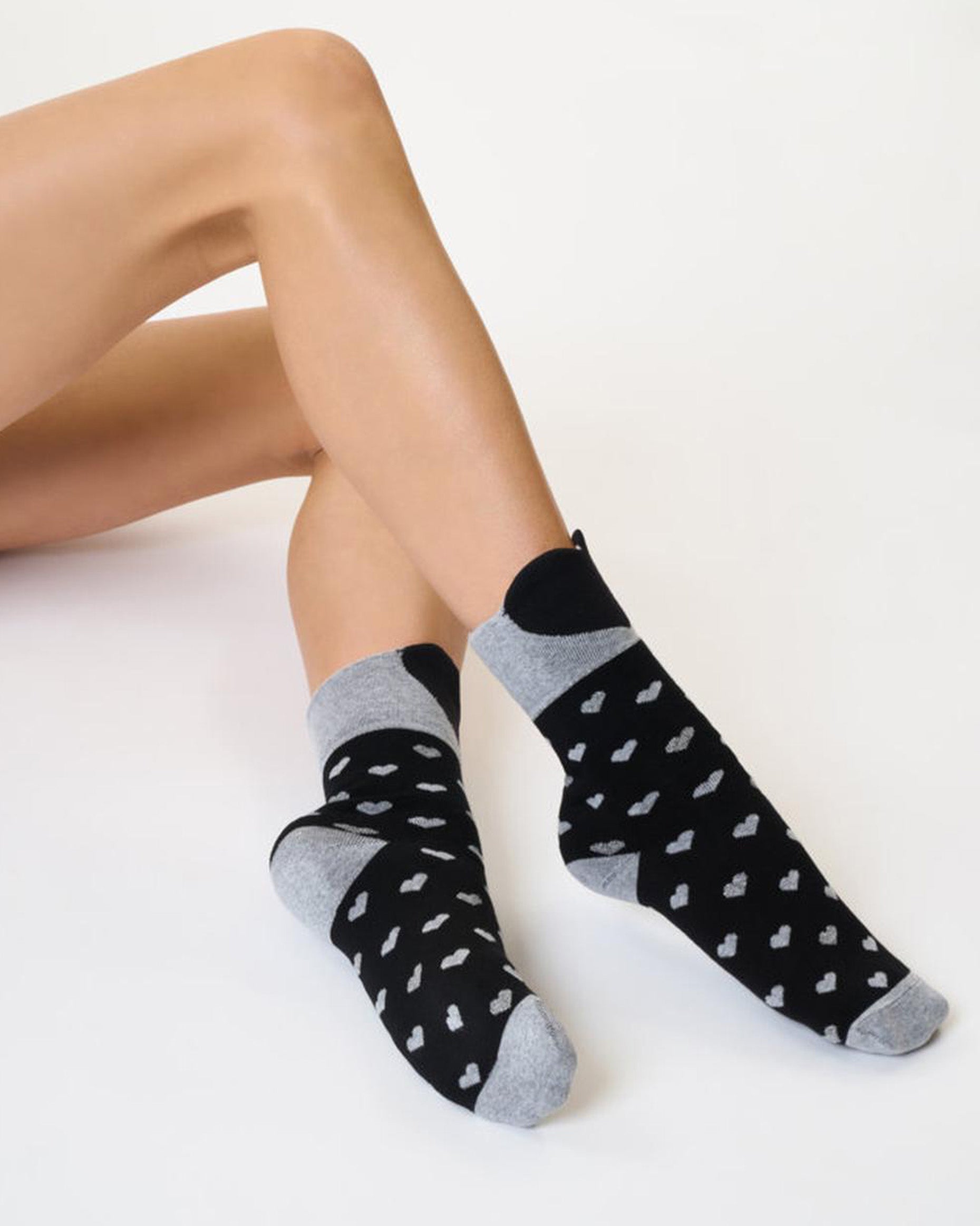SiSi Hearts Slipper Sock - Warm black cotton ankle socks with a warm terry lining, all over heart pattern in grey and silver lurex, deep comfort cuff with a large heart shape to the front, anti slip grippers on the sole with sparkly glitter and grey toe and heel.