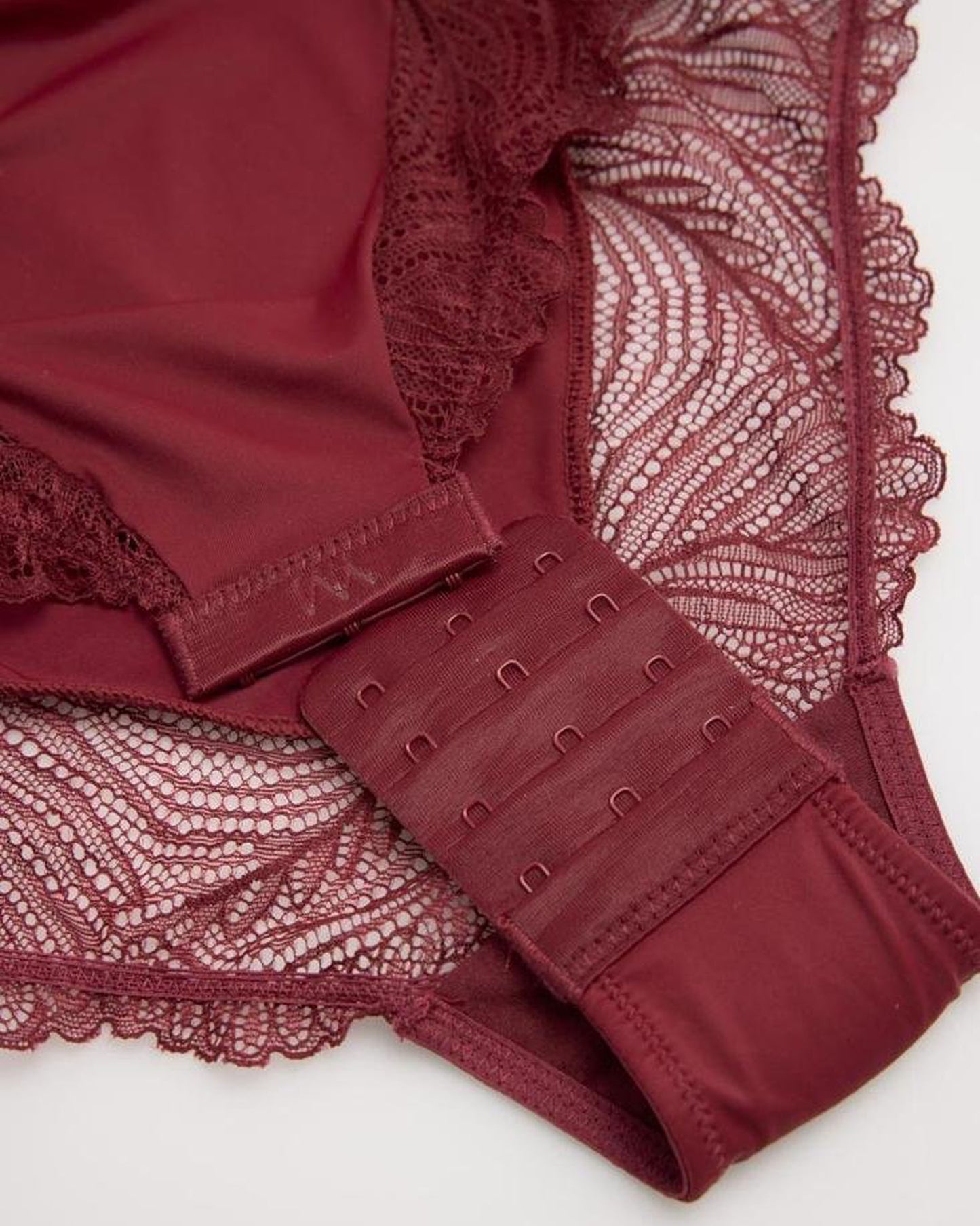 Close-up of a burgundy lace body-top hook and eye closures on a white background