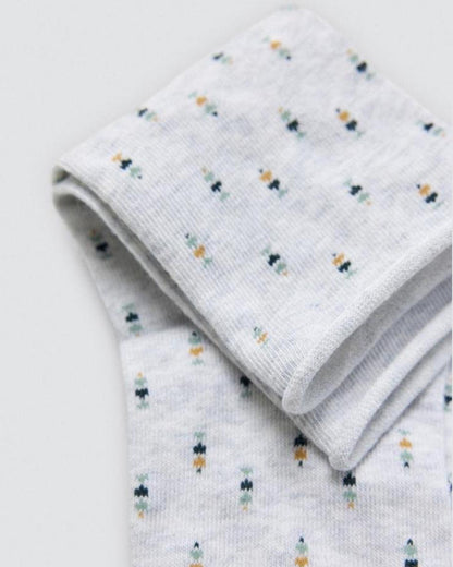 Folded light grey socks with a small colourful patterns on a light grey background