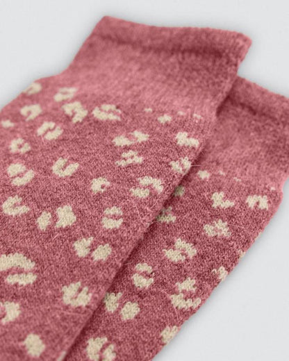 Pink socks with beige patterns on a light gray background, cuff detail.