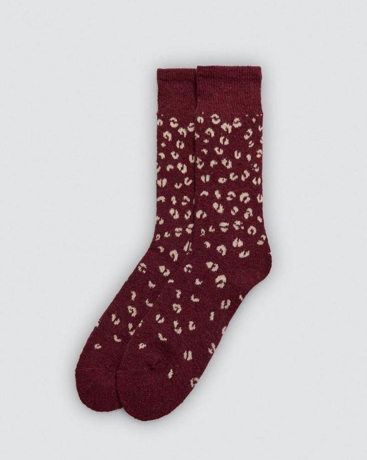 Maroon sock with beige leopard print pattern on a light gray background