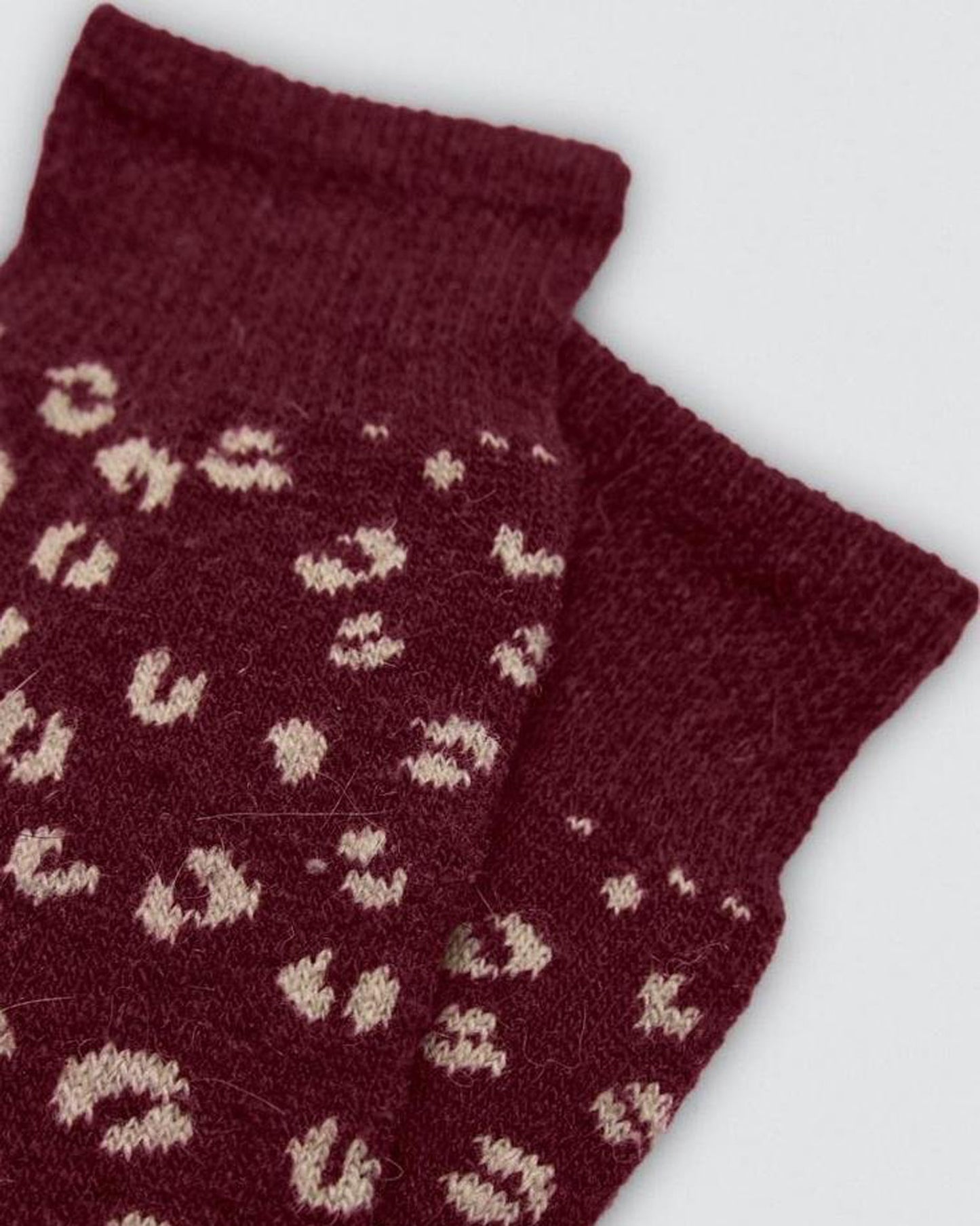Maroon socks with beige pattern on a white background, cuff detail.