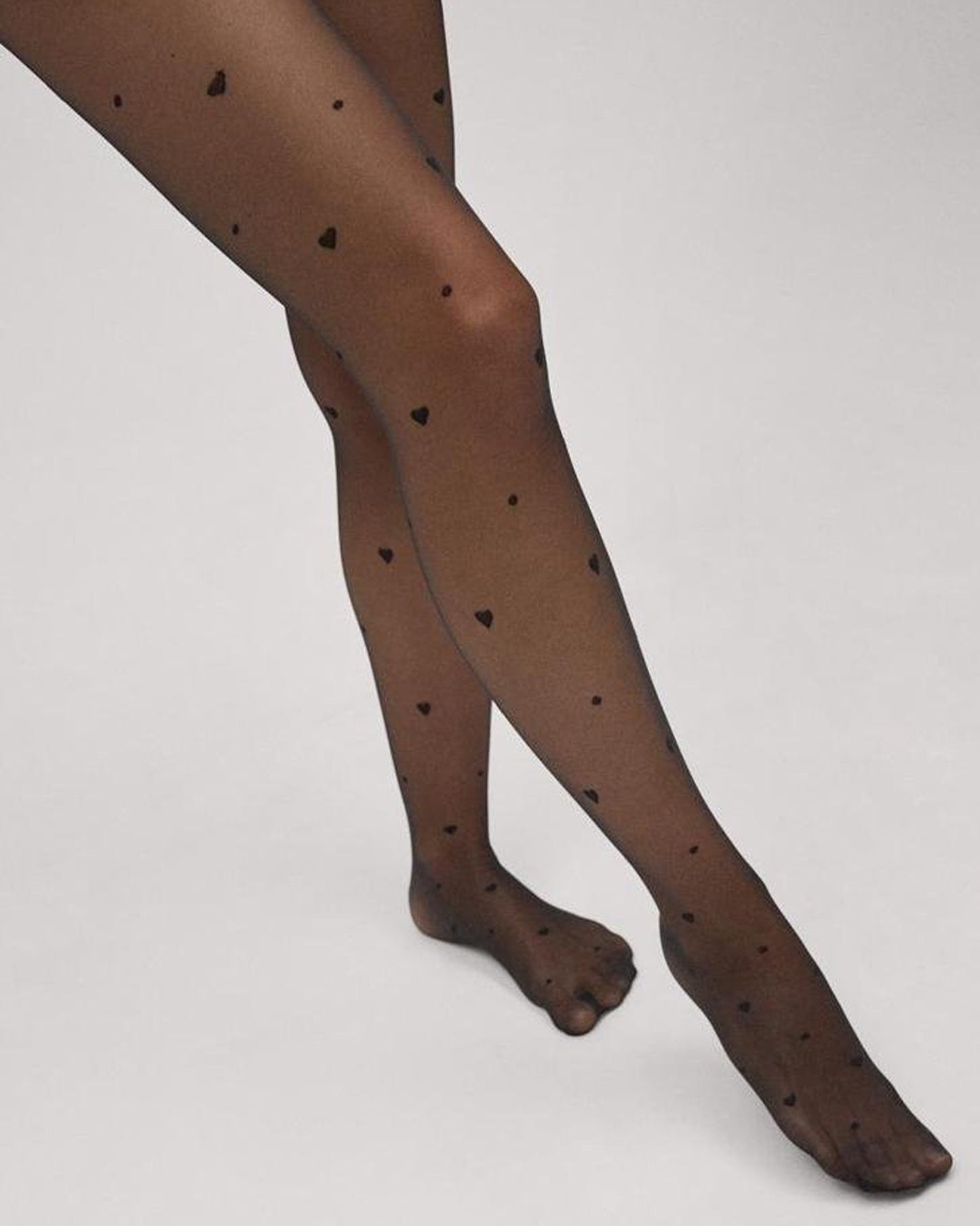 Sheer black fashion tights with a small woven heart and spot pattern.