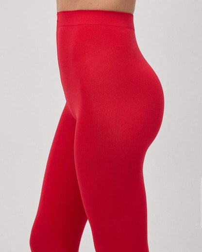 Close up of waist of red opaque tights worn by a model with light grey backdrop