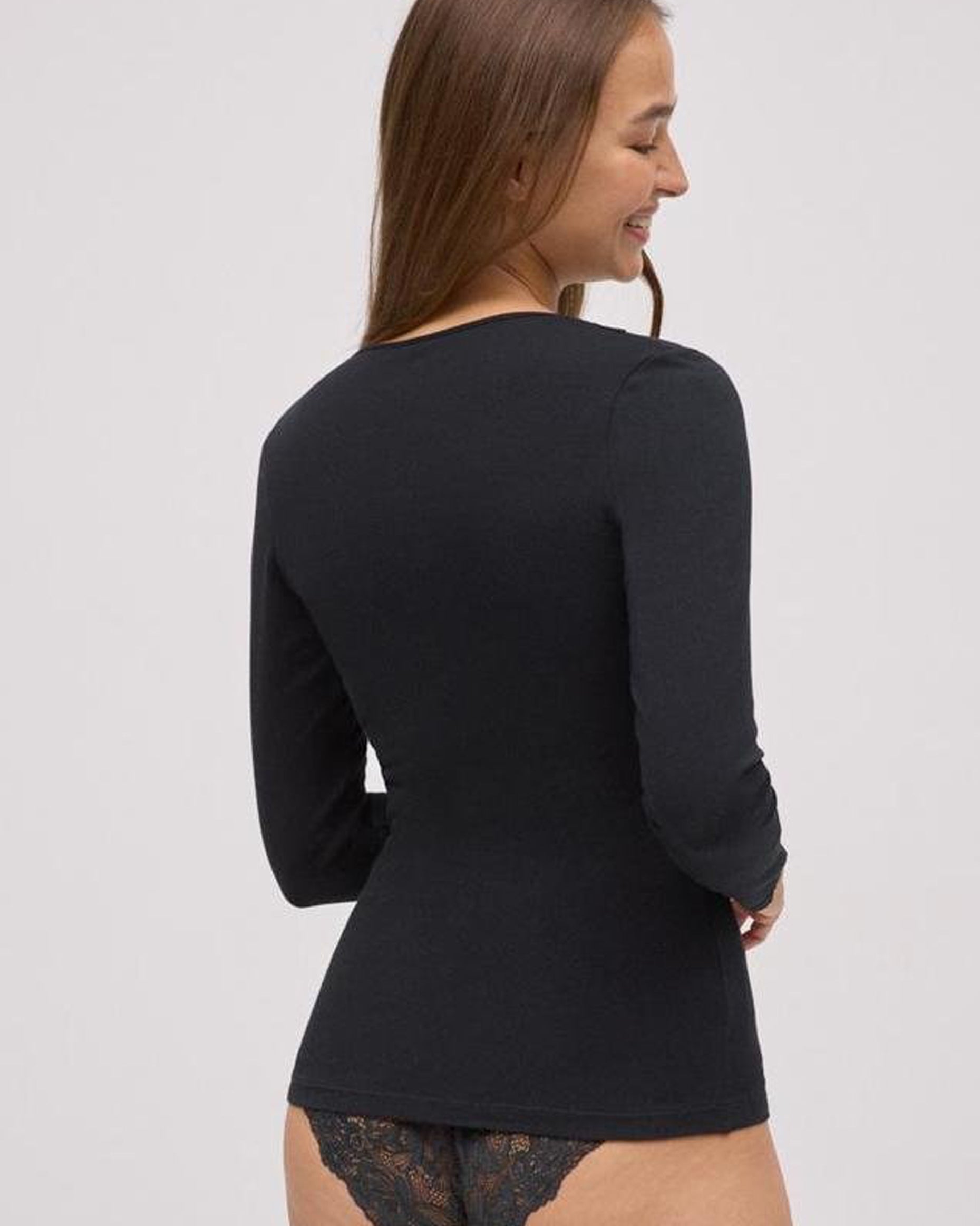 Woman wearing a black long-sleeve top on a plain background, back view.