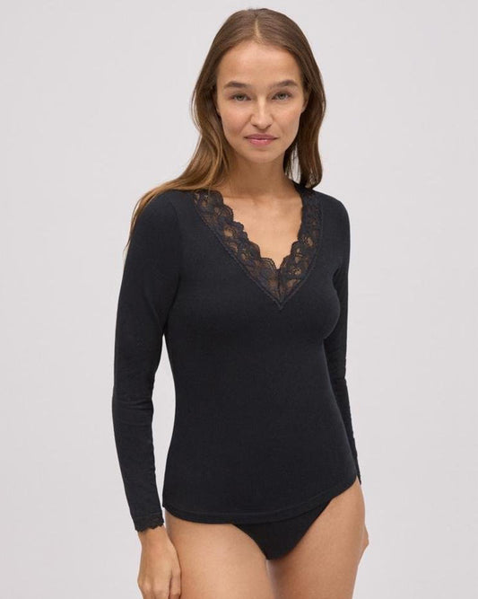 Woman wearing a black long-sleeve top with lace neckline on a gray background