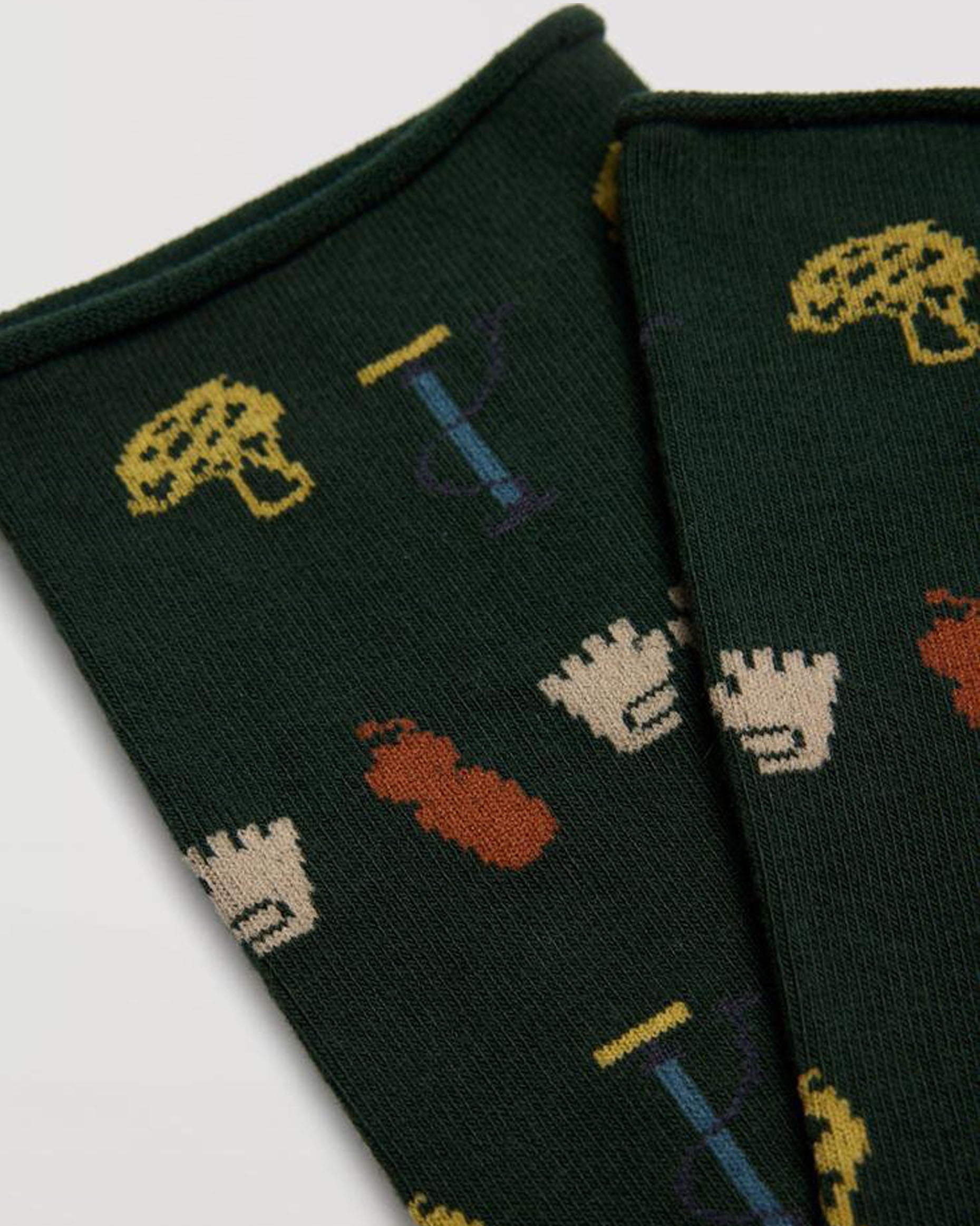 Dark green cotton mix crew length no cuff roll top ankle socks with an all over cycling themed pattern made up of bicycle pump, helmet, gloves and water bottle in yellow, rust, blue and cream.