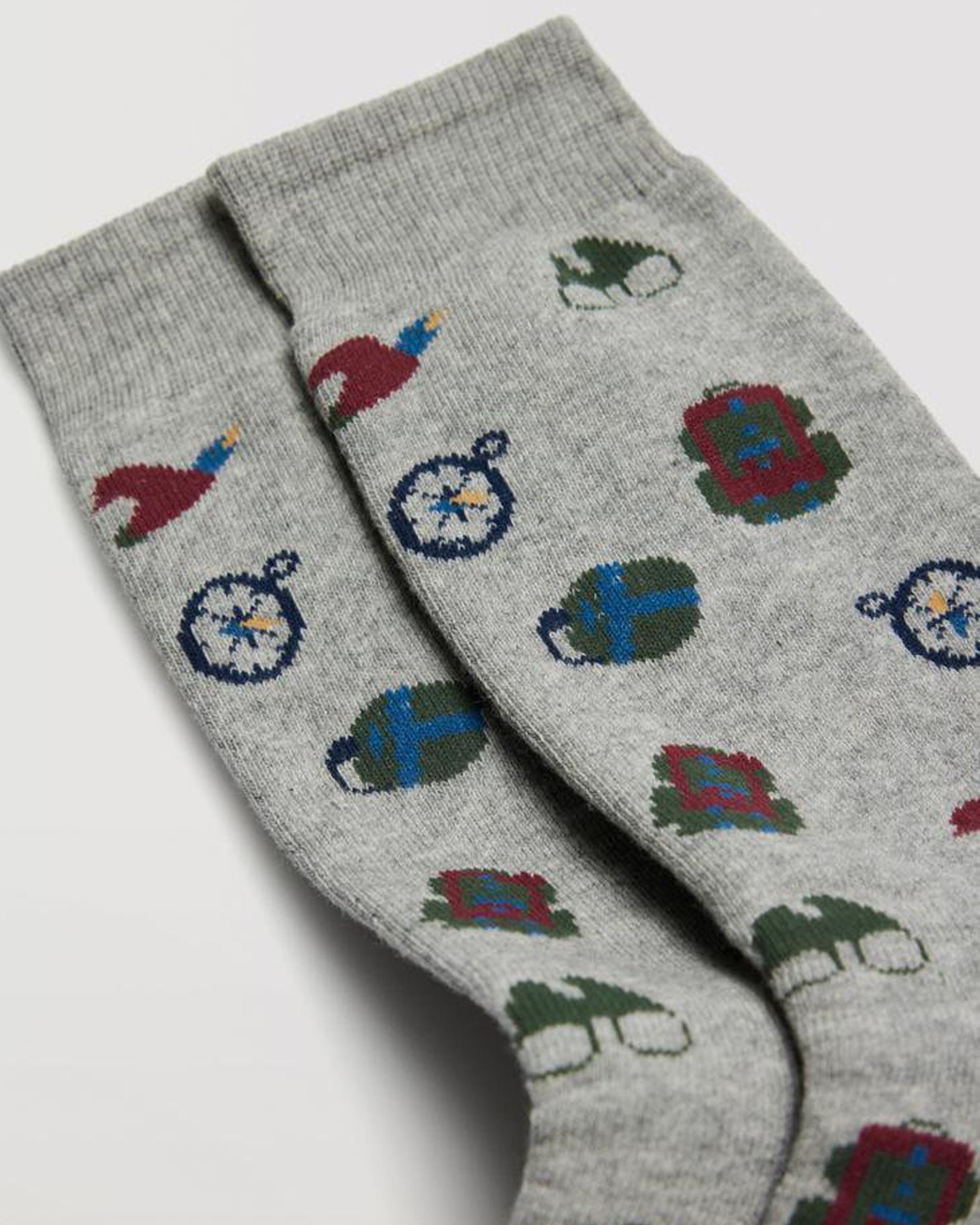 Light grey cotton mix crew length terry lined ankle socks with an all over explorer themed pattern of a compass, backpack, binoculars, water bottle and ducks in wine, dark green, blue and yellow with deep elasticated comfort cuff.
