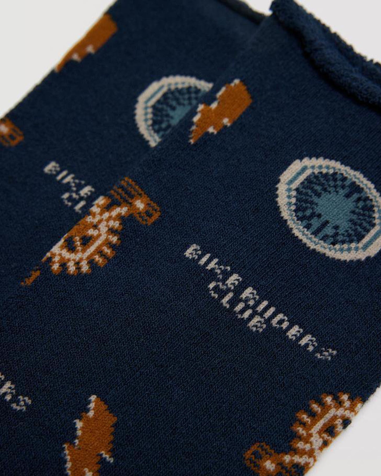Thick and warm terry lined navy blue cotton crew length soft no cuff ankle socks with an all over pattern of bicycle parts (wheels and pedals), lightning bolts and the text "bike riders club".