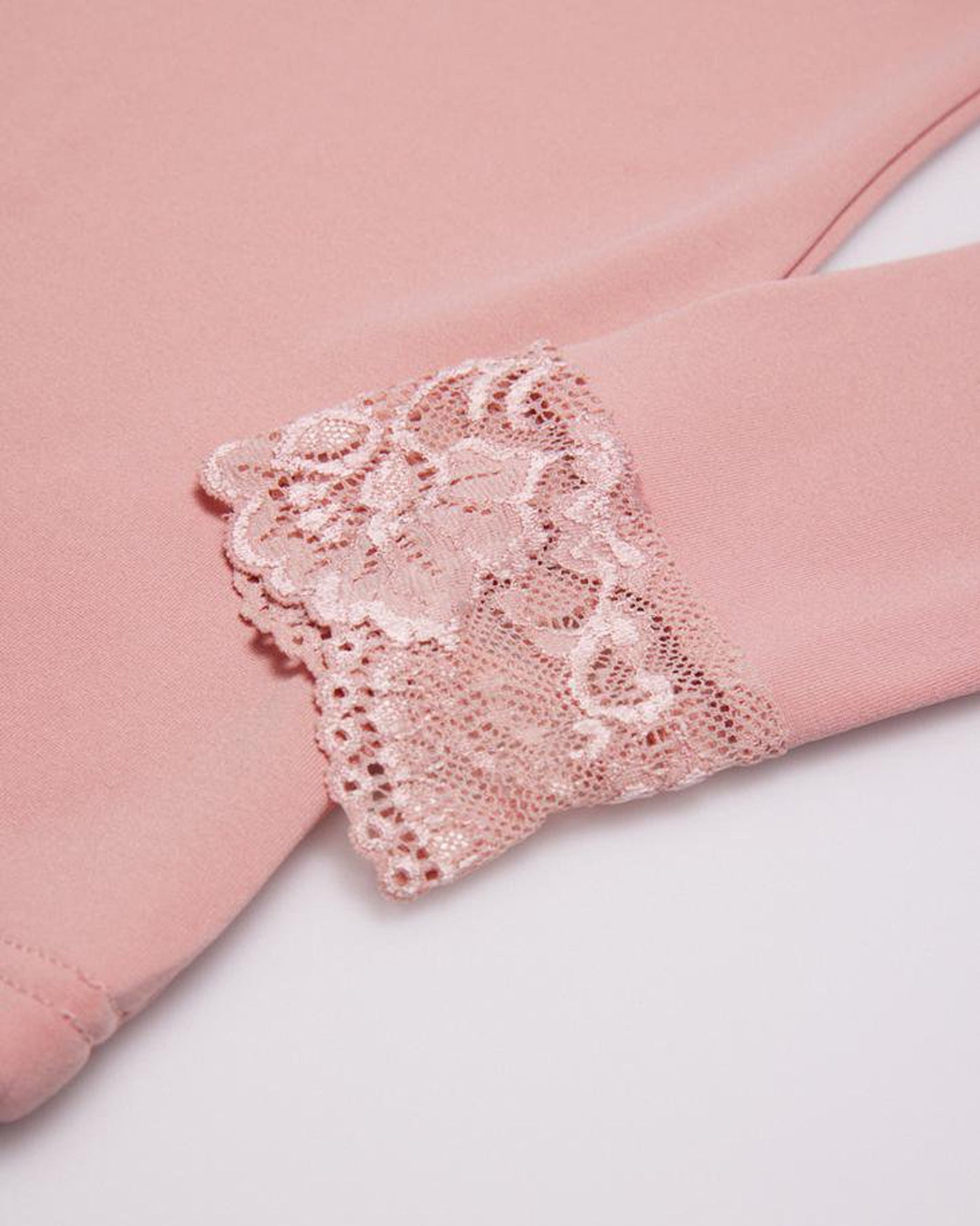 Blush pink top with floral lace cuff detail.